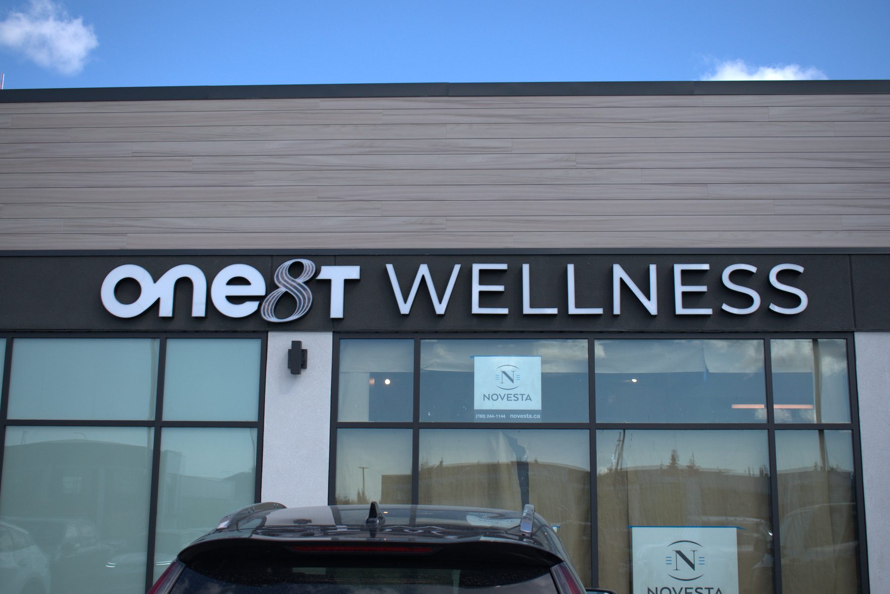 Exterior storefront with wood-look siding and dimensional lettering — ONE8T (West District)