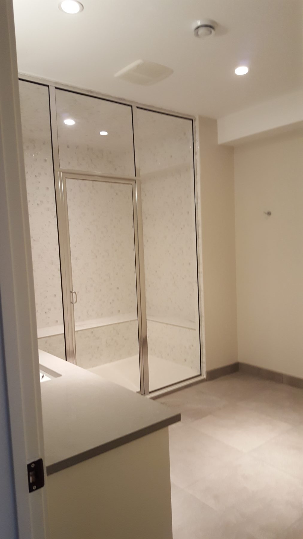 Shower stall under construction with framed glass doors and marble walls — Briar Hill