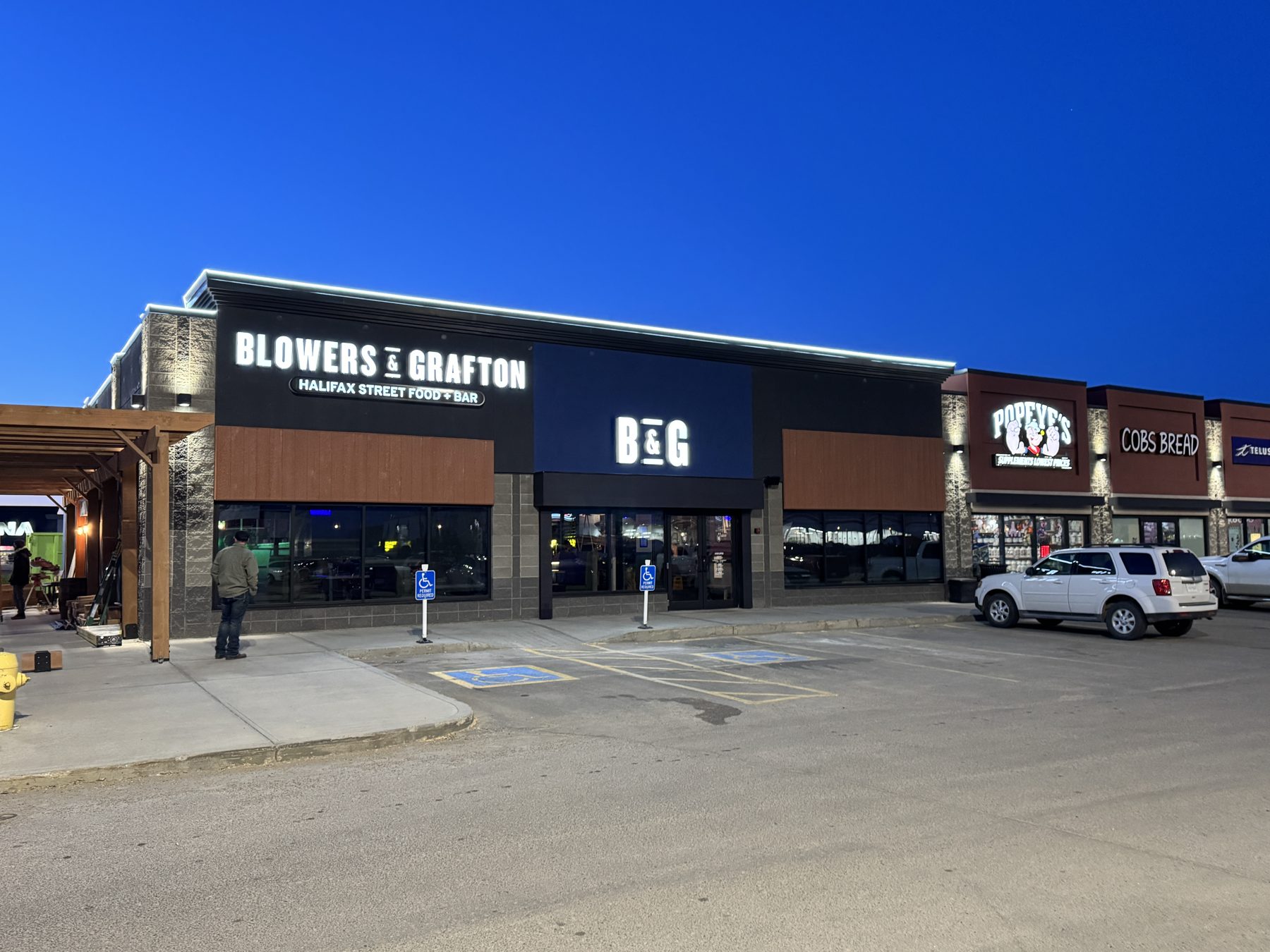 Storefront with illuminated signage and concrete parking lot — Blowers and Grafton (Lloydminster)