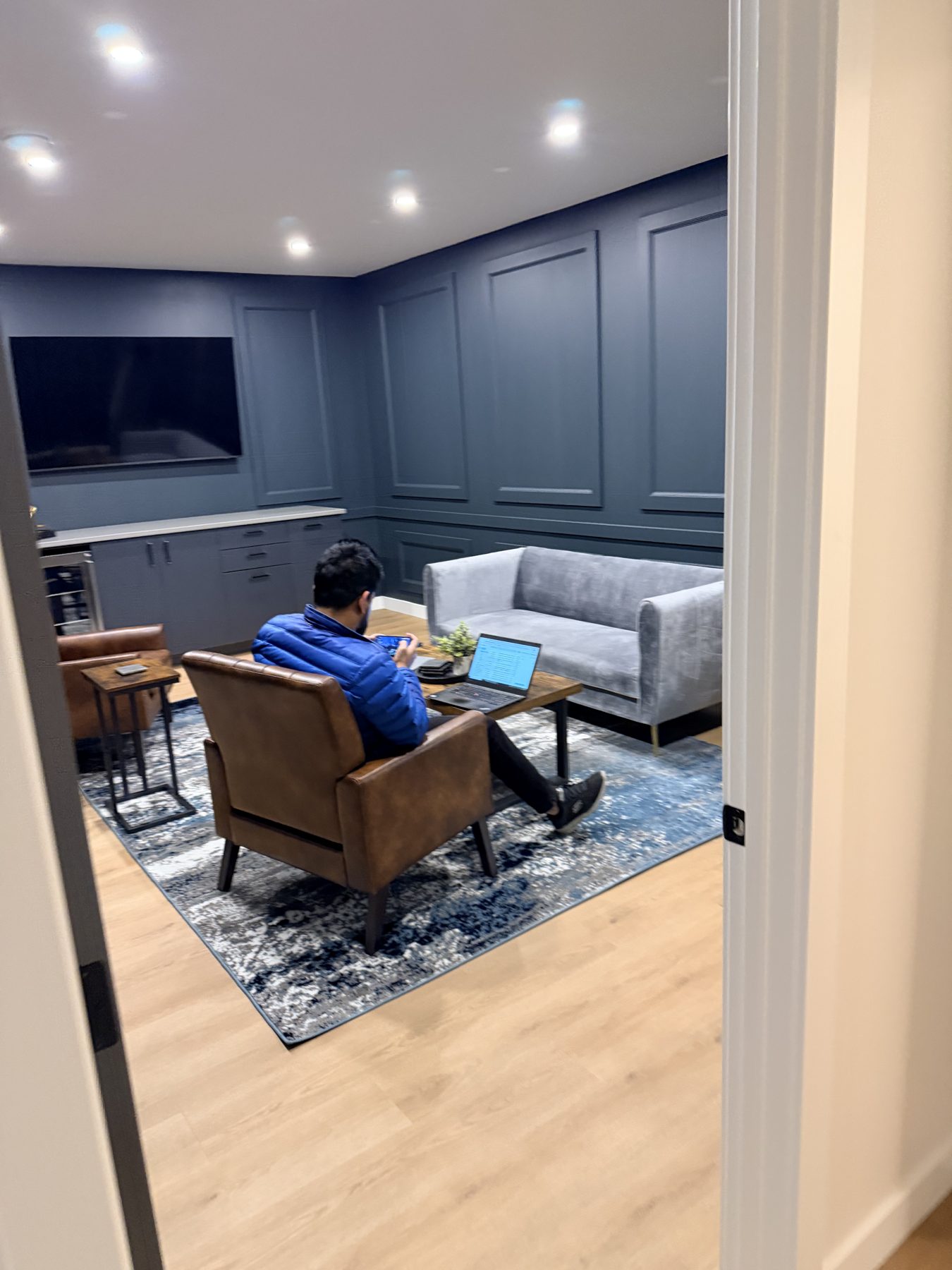 Living room with blue walls, wood floor, and plush furniture — The Barron Venue