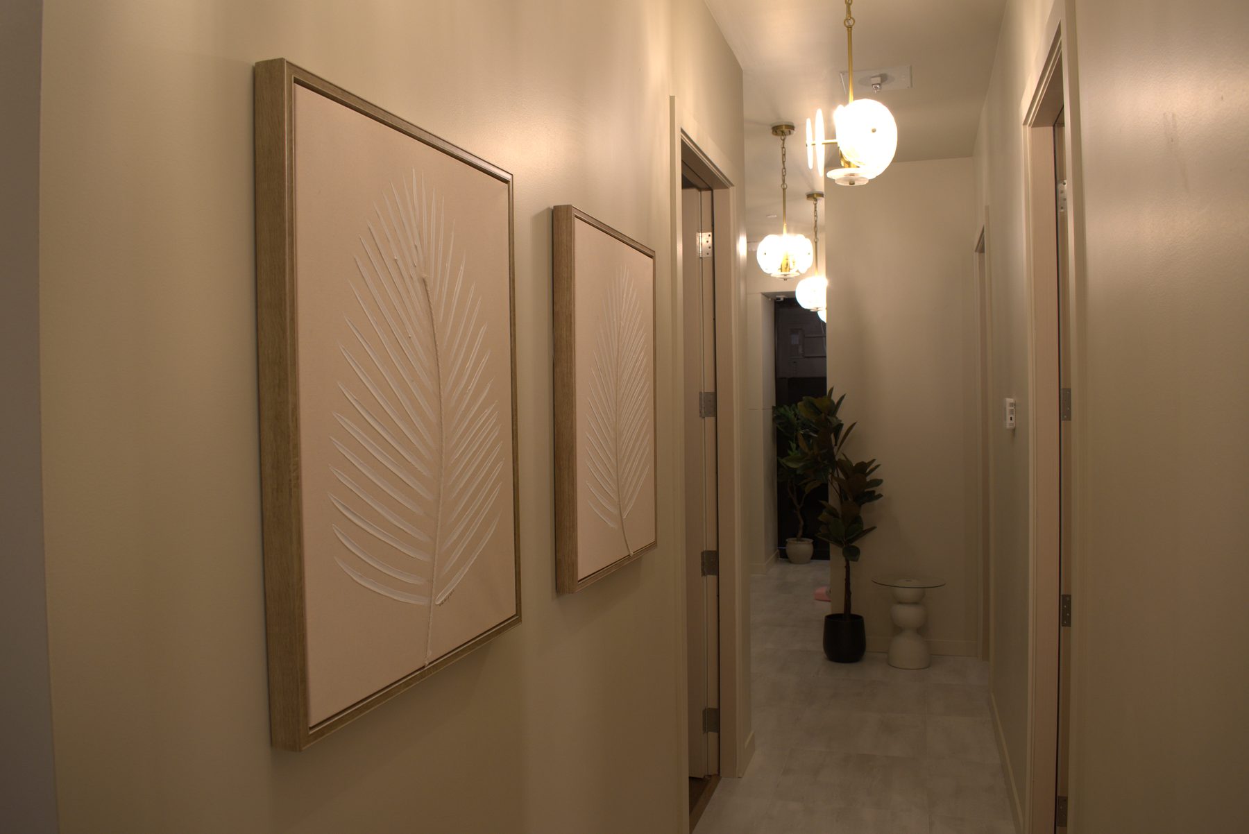 Hallway with neutral walls, modern pendant lights, and botanical artwork — Leela Spa (Bankers Hall)