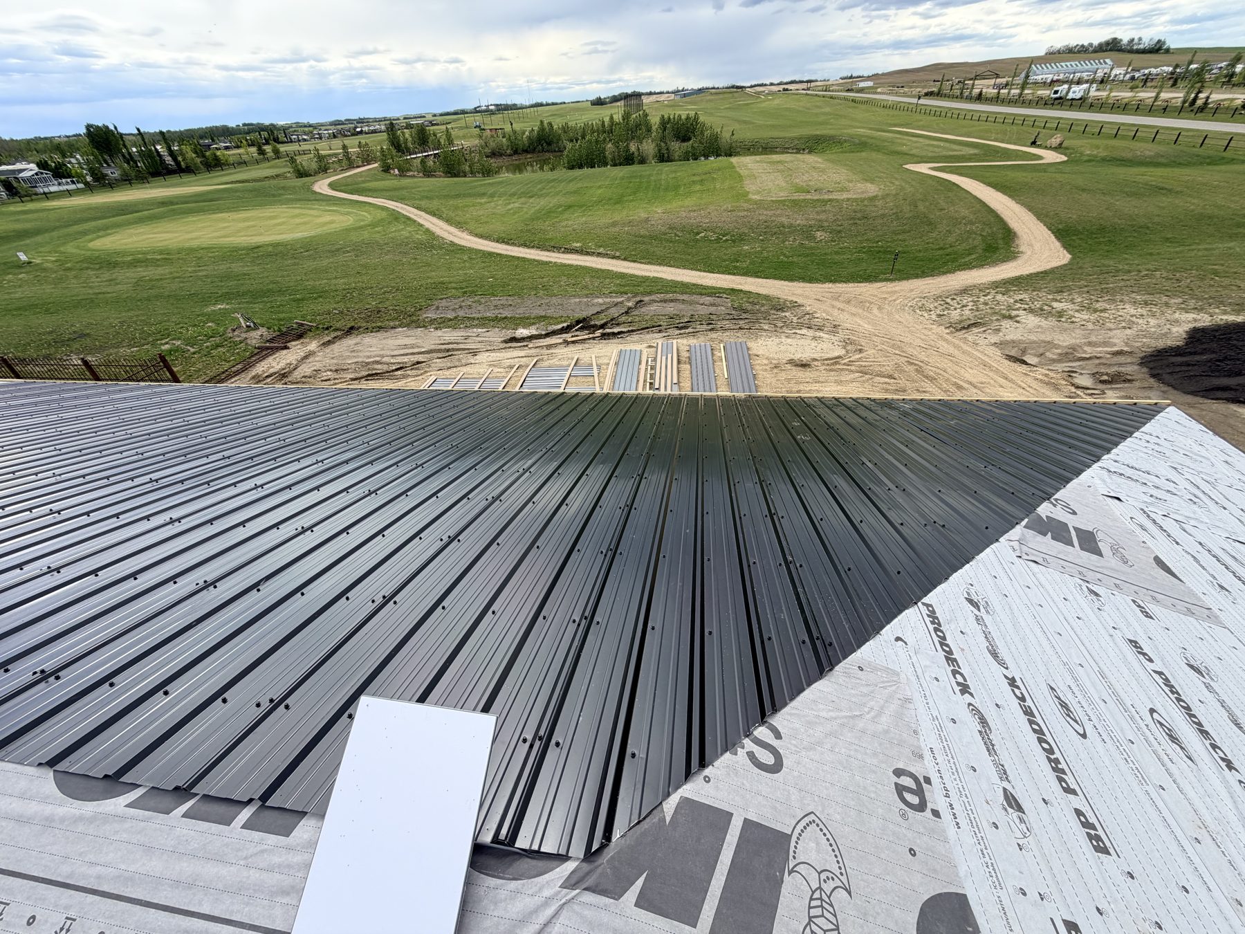 Metal roofing installation over weather barrier, golf course background — Sandy Point (Club House)