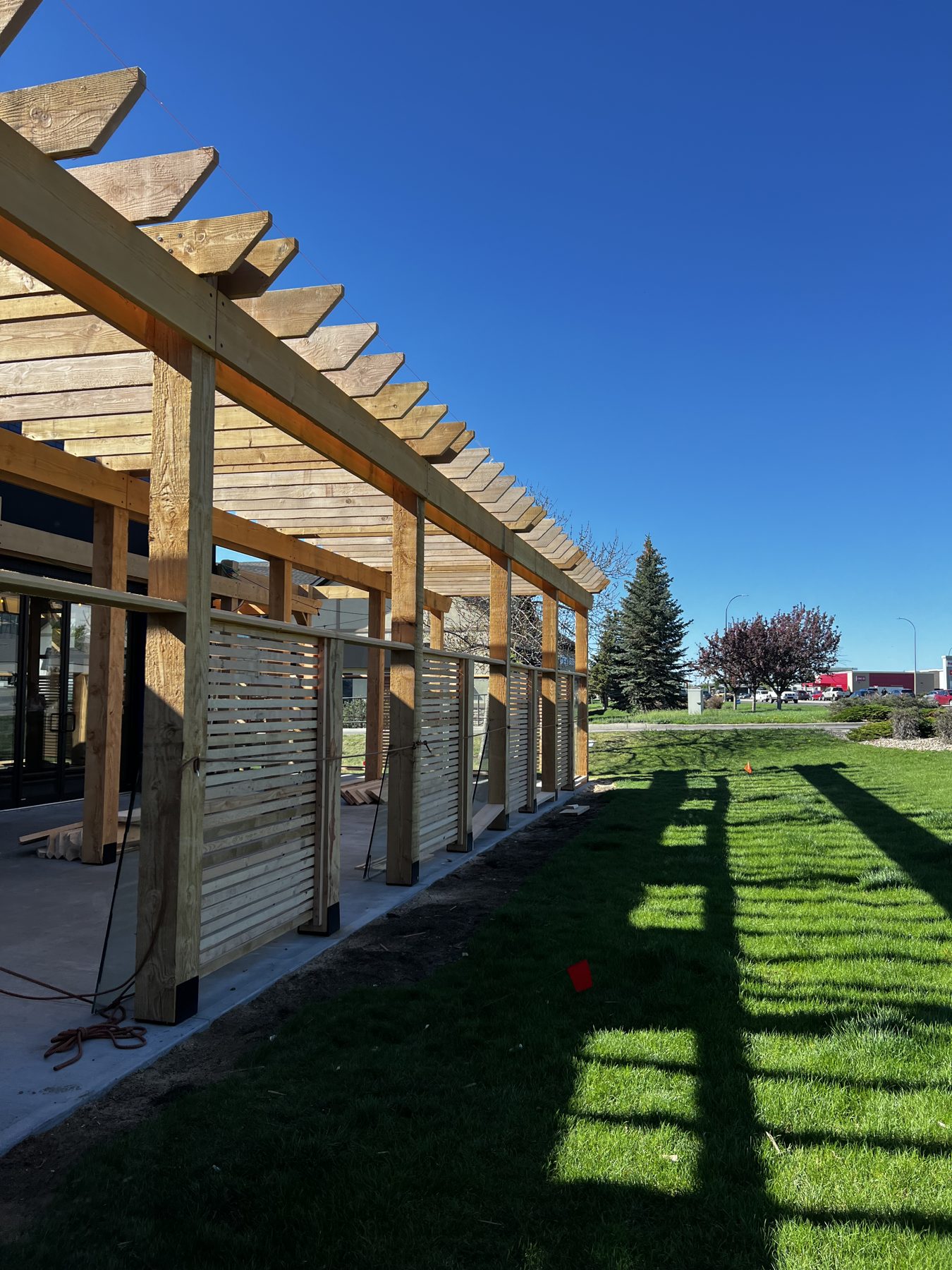 Wooden pergola and slatted screens under construction over concrete patio — Blowers and Grafton (Lethbridge)