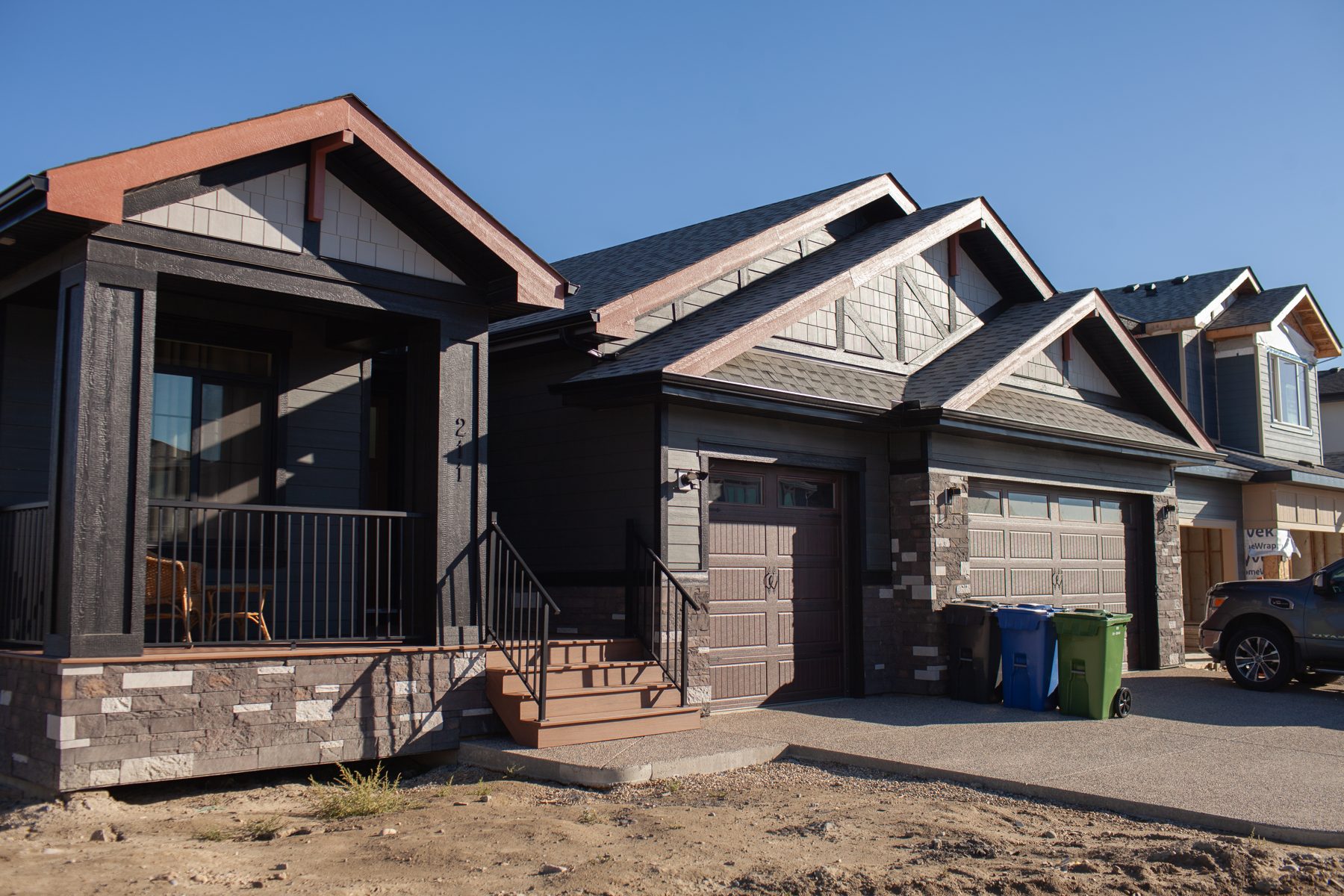 Dark modern homes under construction with stone accents and brown garages — 211 Blackstone Rd