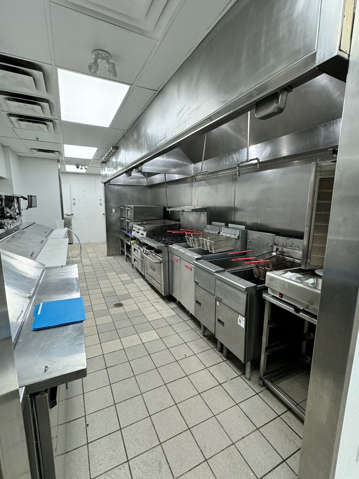 Commercial kitchen with stainless steel fryers, griddle, and exhaust hood — Blowers and Grafton (Medicine Hat)
