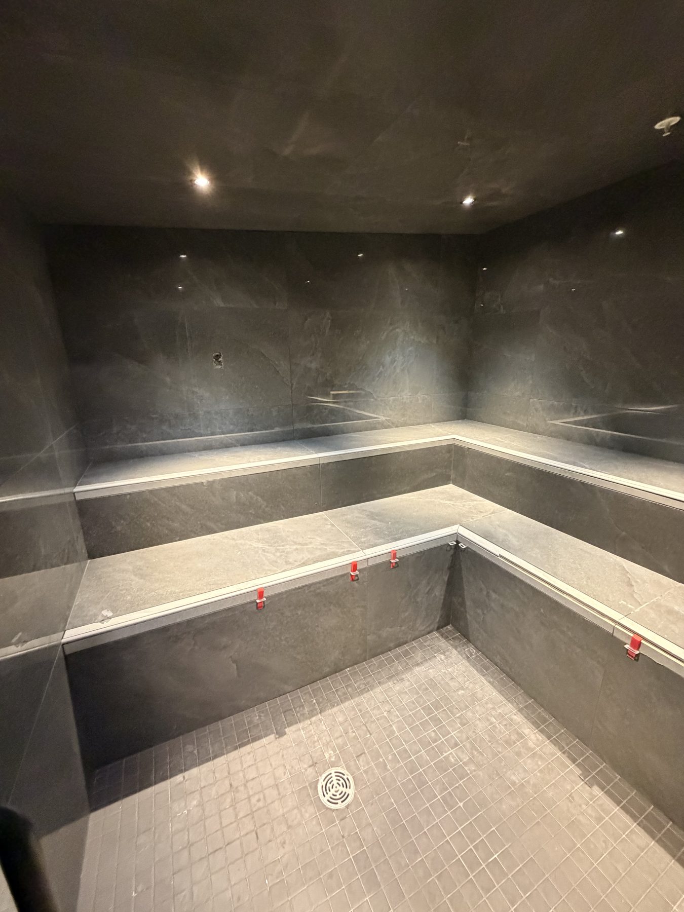 Steam room under construction with gray tile and built-in benches — Cedar Steam and Spa (Trinity Hills)