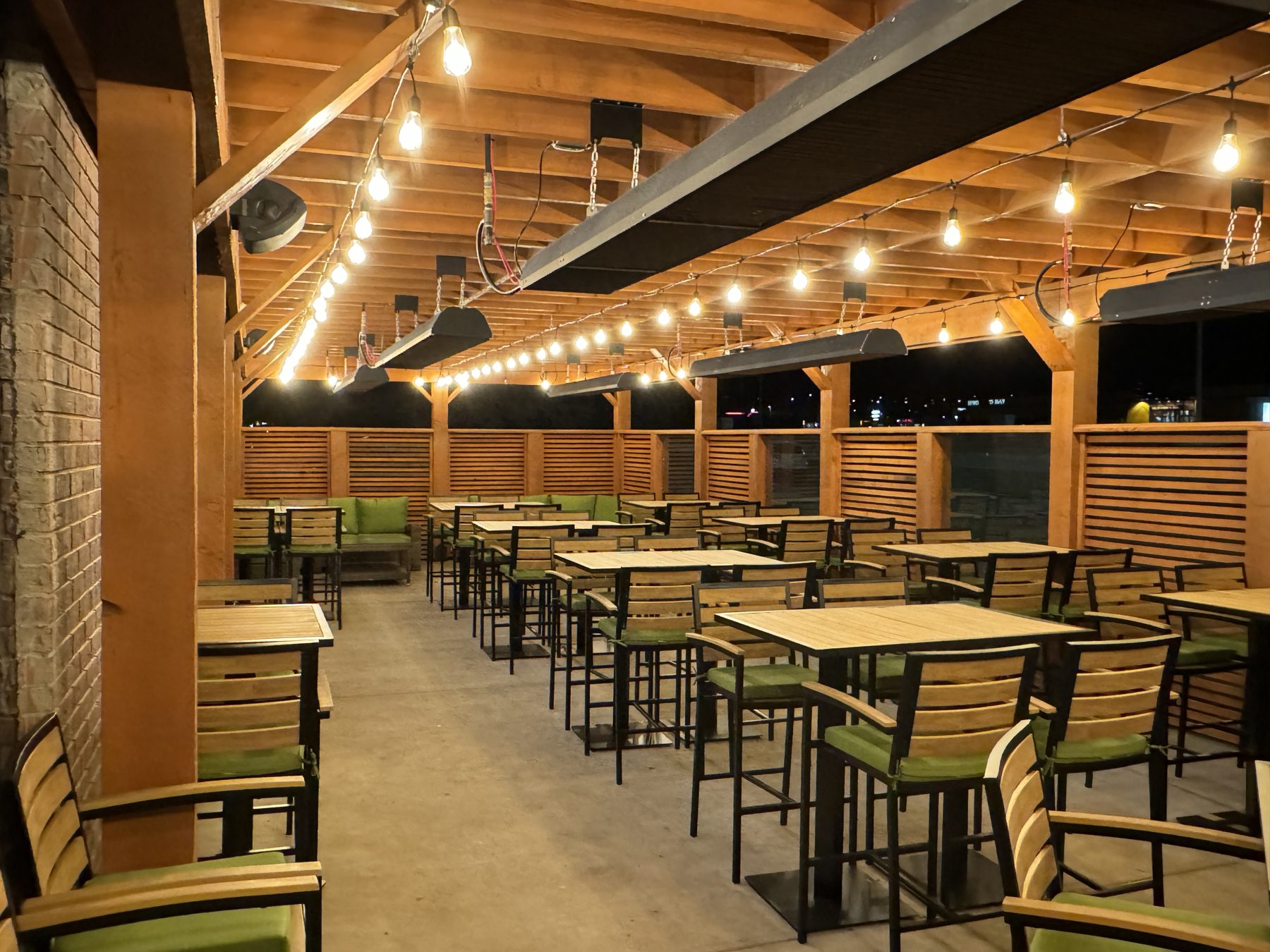Outdoor dining area with wooden tables, green chairs, and string lights — Blowers and Grafton (Medicine Hat)