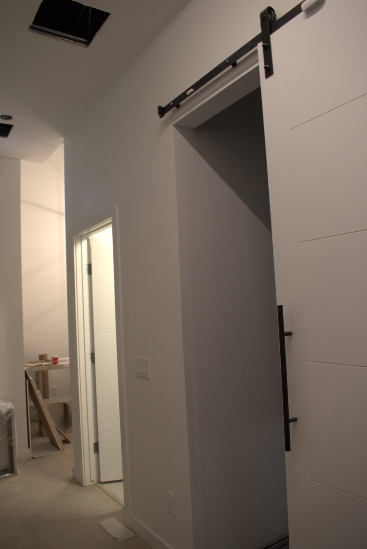 Hallway renovation with white walls, barn door, and open ceiling panel — Big Buns (Bowness)