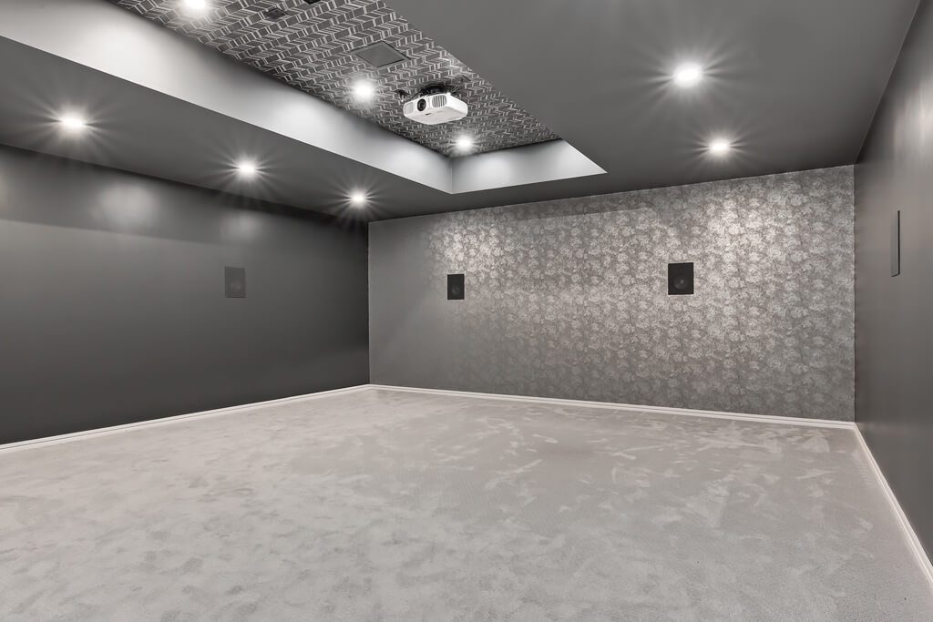 Home theater room with gray carpet, dark walls, and patterned ceiling — Blanc de Blanc