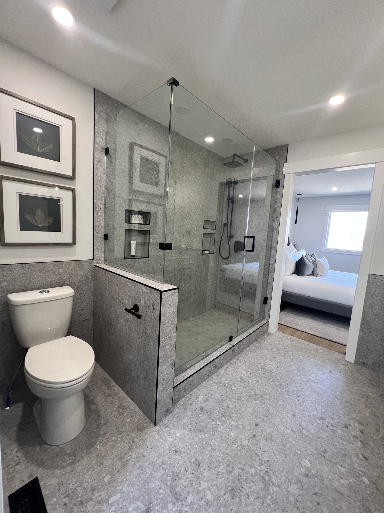 Modern bathroom renovation with glass shower, toilet, and view into bedroom — 720 Lake Twintree Crescent SE, Calgary