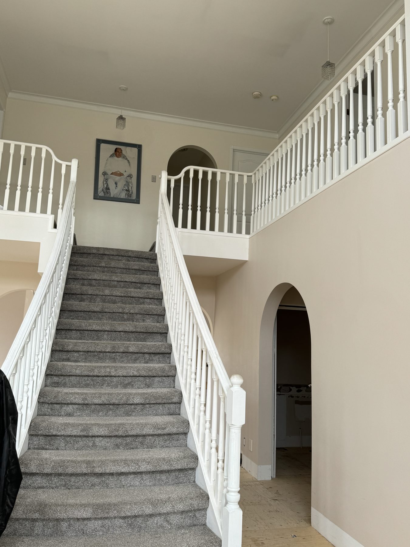 Two-story foyer with carpeted stairs and white balusters — 14 Lochend Drive, Cochrane