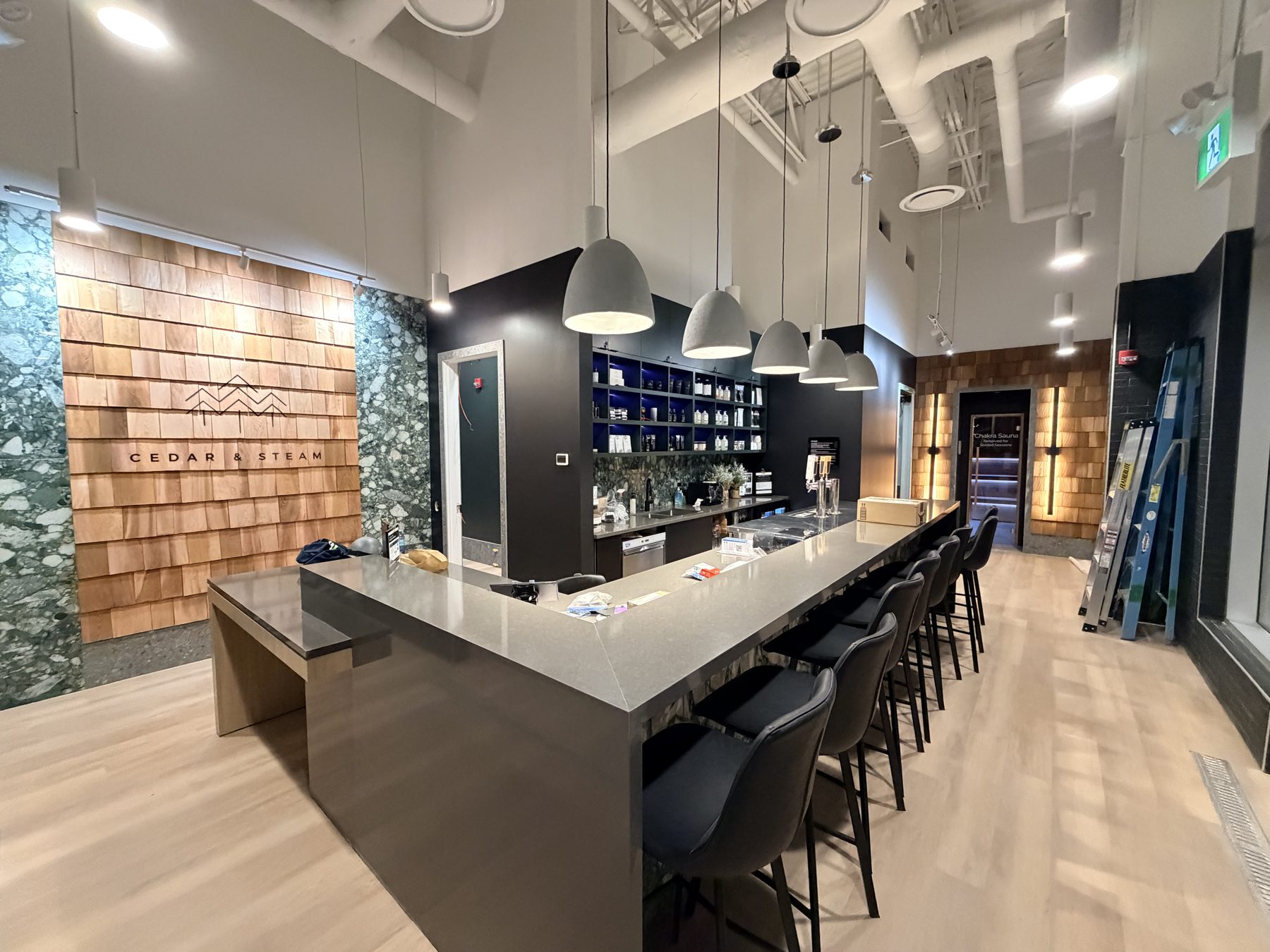 Modern bar with grey countertop, wood accents, and pendant lighting nearing completion — Cedar Steam and Spa (Trinity Hills)