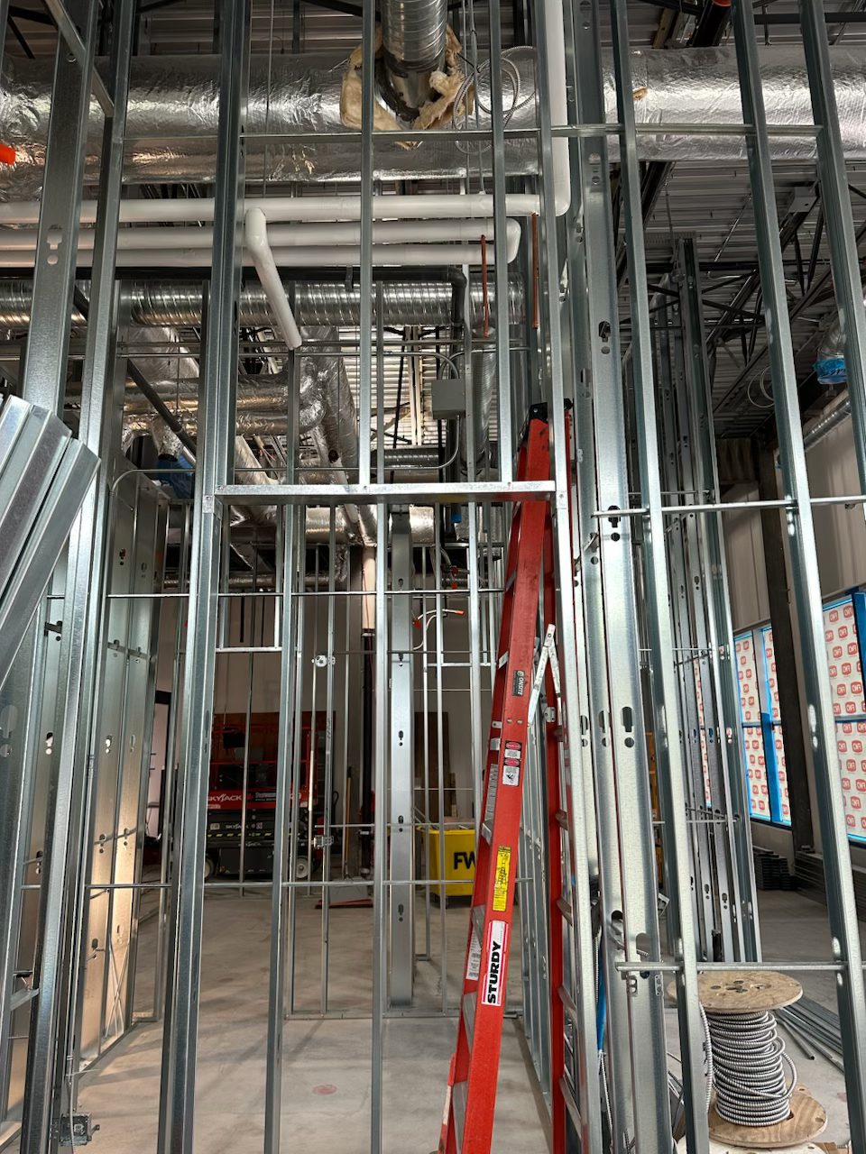 Metal framing, pipes, and insulation in an unfinished room — Blowers and Grafton (Red Deer)