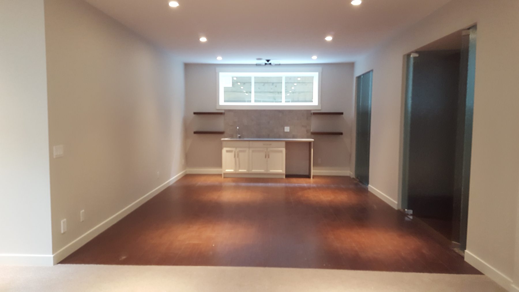Room with unfinished bar, wood floor, and glass door — Briar Hill