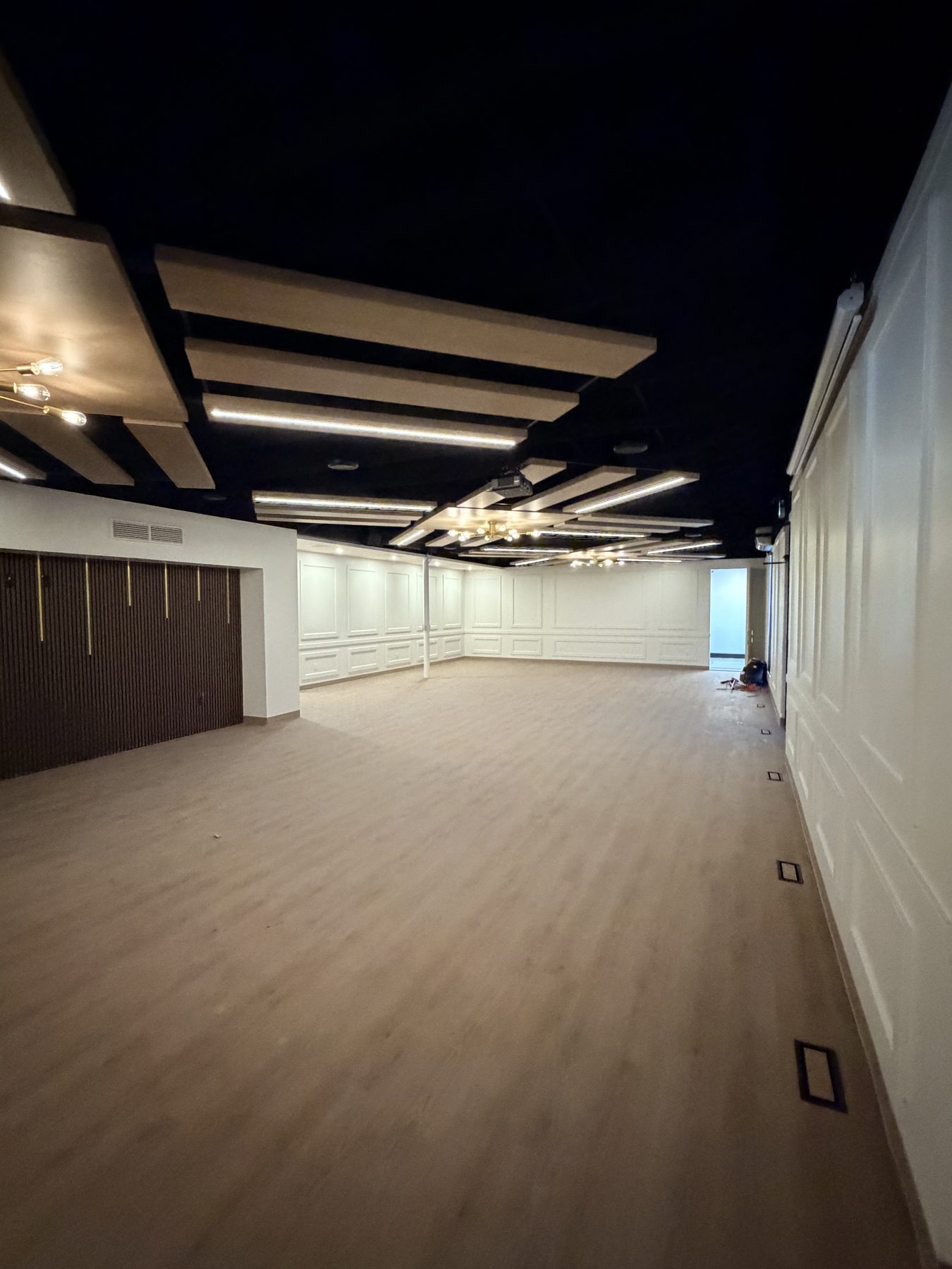 Unfinished room with wood floor, wainscoting, and decorative ceiling lights — The Barron Venue
