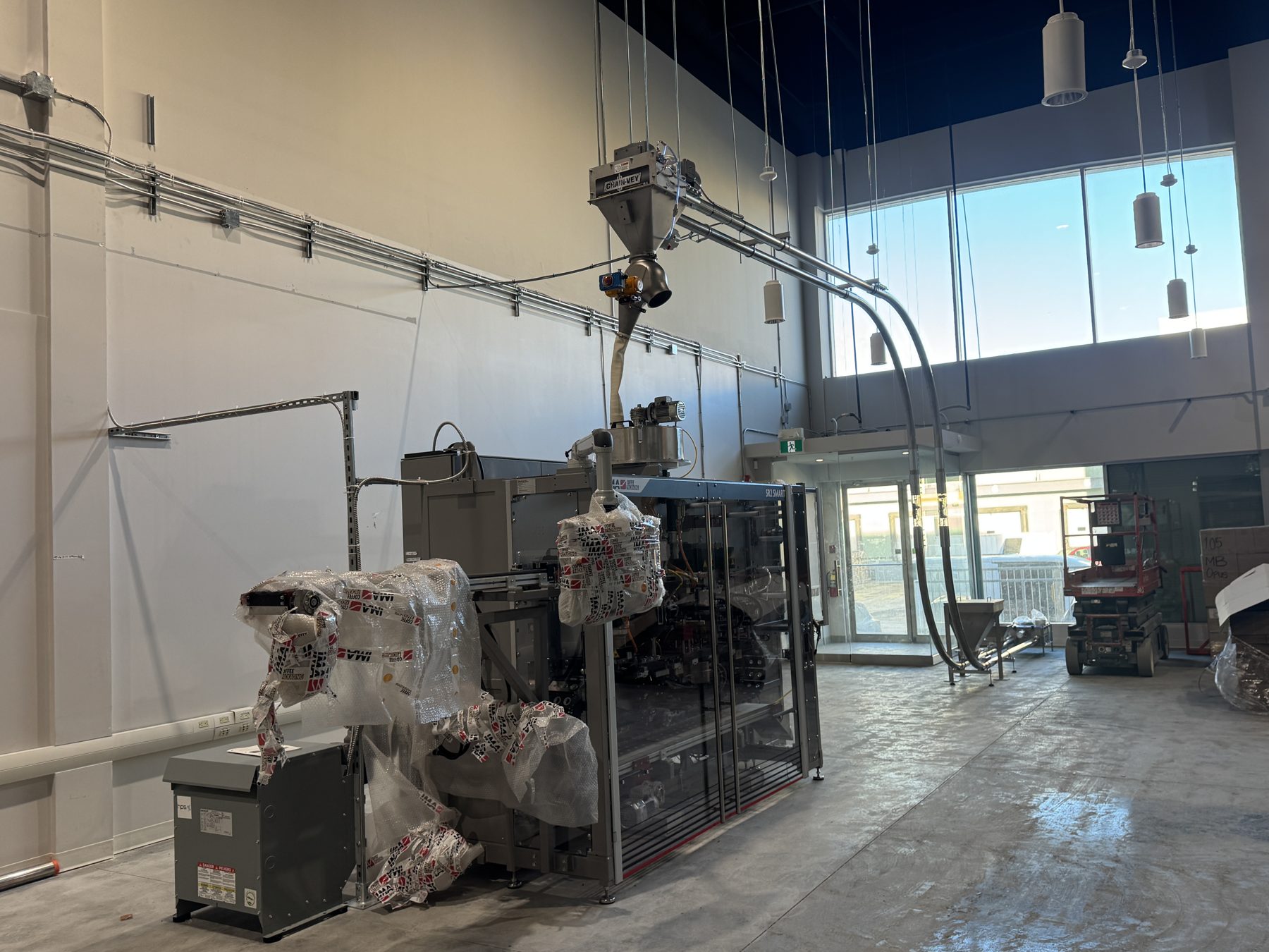 Industrial packing machine installation in a new factory space — Eight Ounce Coffee