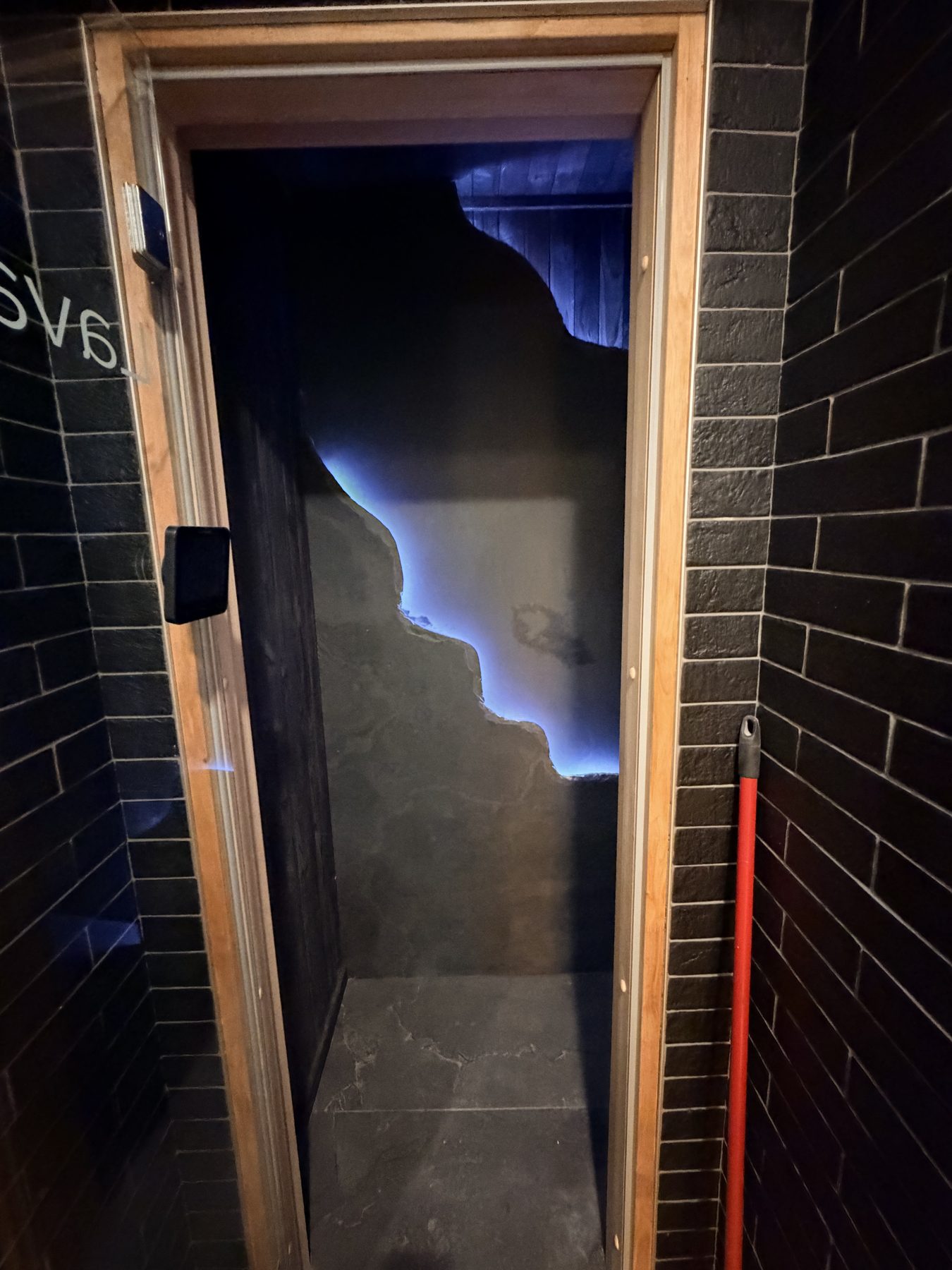 Shower stall with black tile, wood frame, and blue lighting — Cedar Steam and Spa (Trinity Hills)