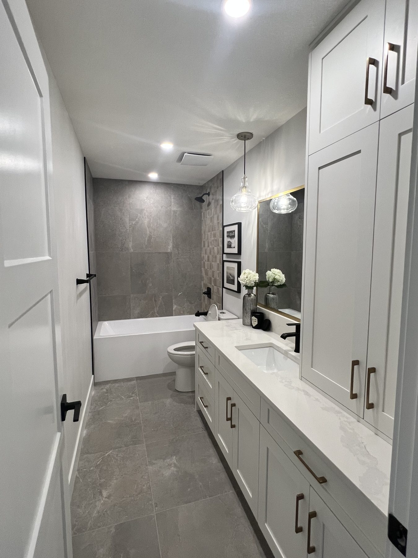 Modern bathroom renovation with gray marble tile and white vanity — 720 Lake Twintree Crescent SE, Calgary