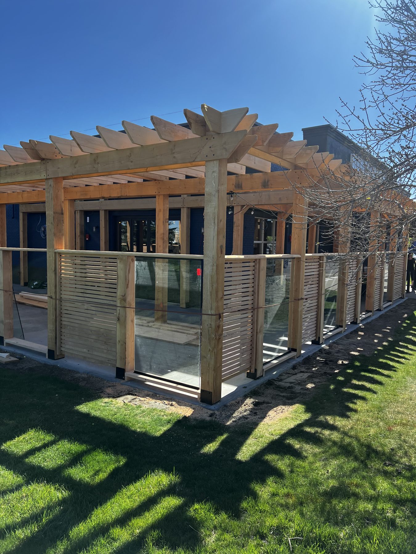 Outdoor patio construction with wooden pergola and glass railing installation — Blowers and Grafton (Lethbridge)