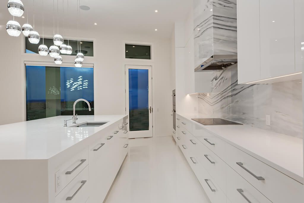 Modern white kitchen island, counters, and cabinets with marble backsplash — Blanc de Blanc
