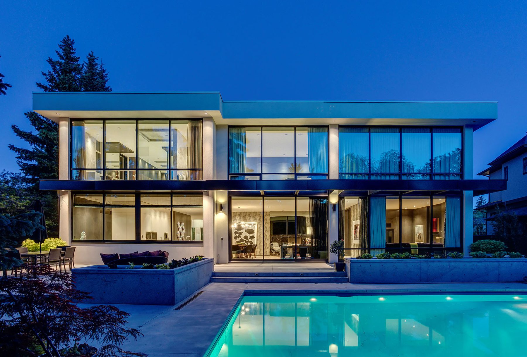 Modern home exterior with large windows, pool, and concrete planters — Modern Family