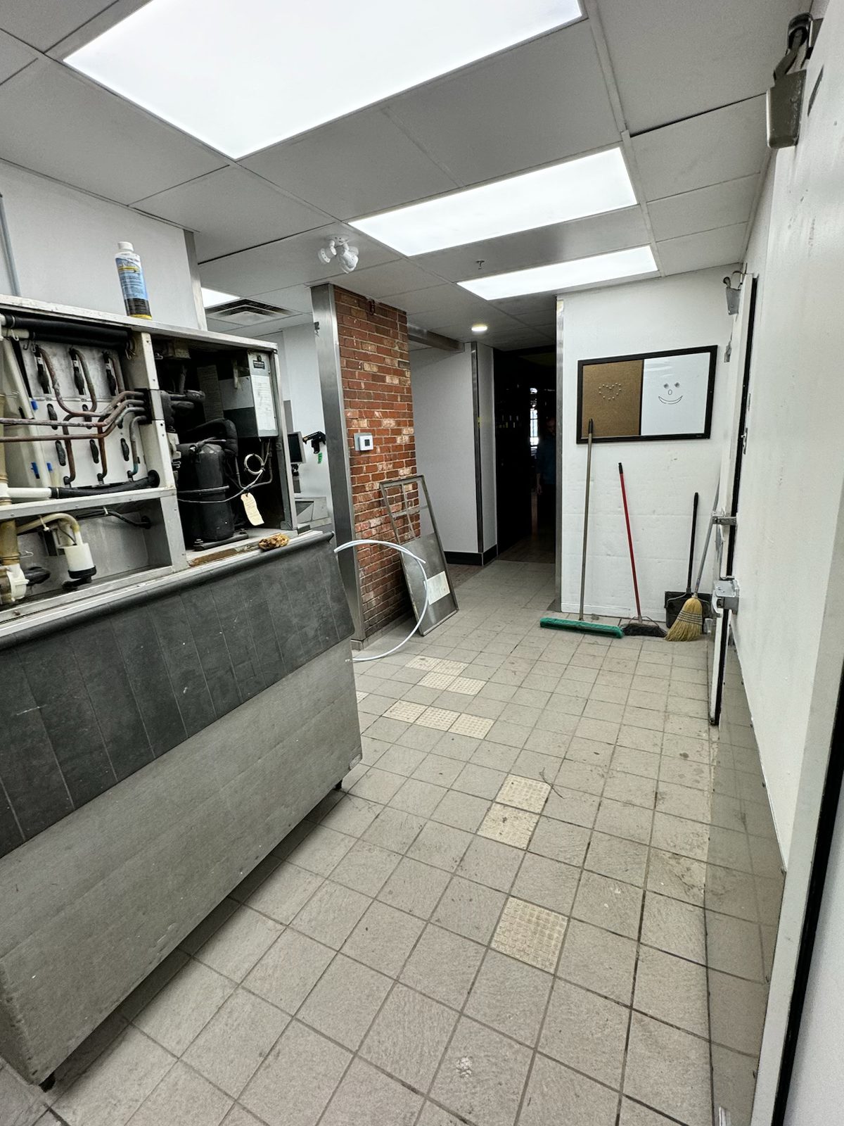 Kitchen renovation with open machinery, brick accent wall, and cleaning supplies — Blowers and Grafton (Medicine Hat)