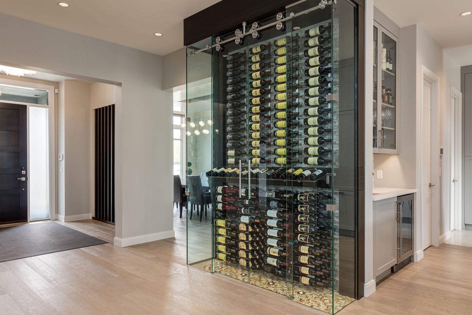 Glass wine cellar with sliding door and extensive bottle storage — The Cellar