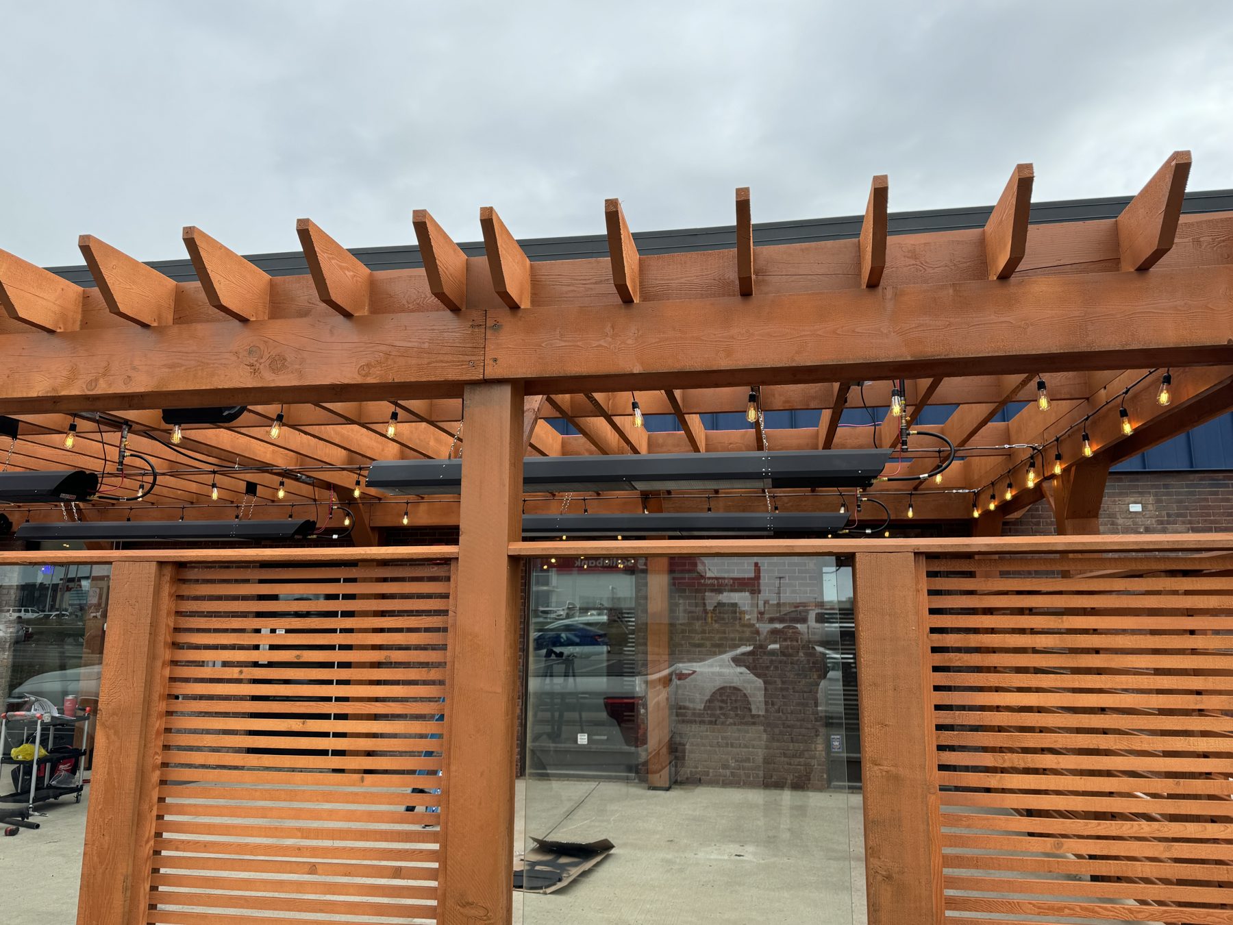 Wooden pergola with string lights, heaters, and slatted dividers — Blowers and Grafton (Medicine Hat)