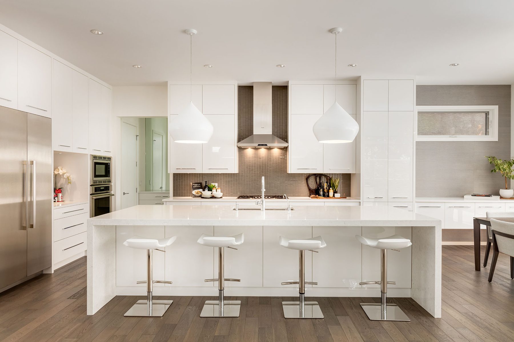 Modern kitchen island with white waterfall counter and bar stools — Casa Blanca