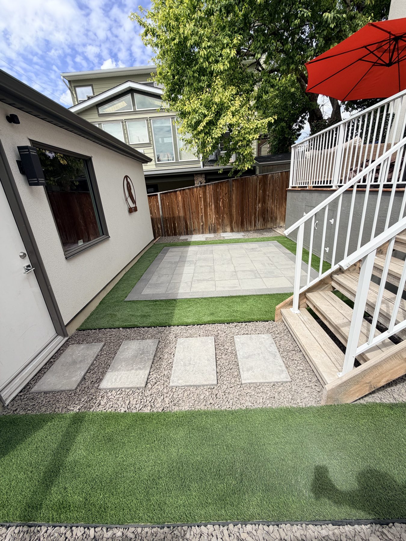 Backyard patio with artificial grass, stone pavers, and wooden stairs — 3505 41 Street SW, Calgary
