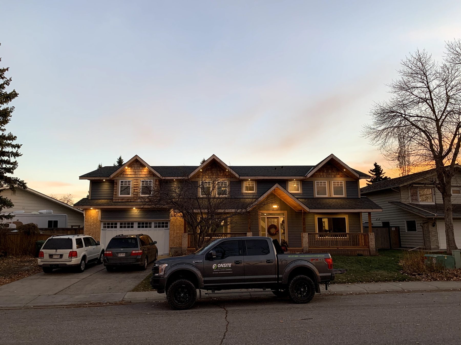 House with new siding and porch, twilight lighting, construction truck parked — 7 Midlake Green SE, Calgary