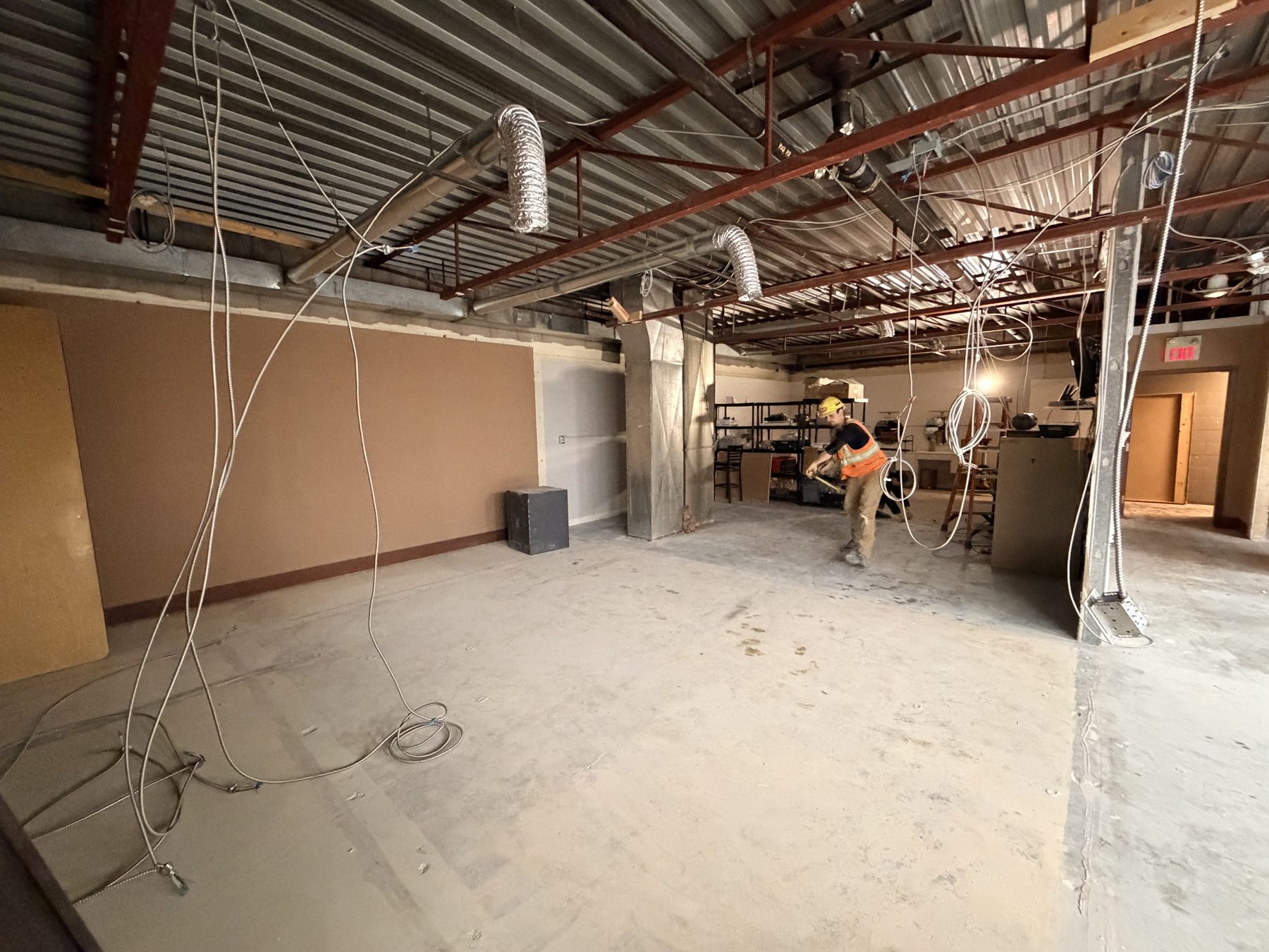 Worker installs HVAC ducting in unfinished room with exposed ceiling — The Barron Venue