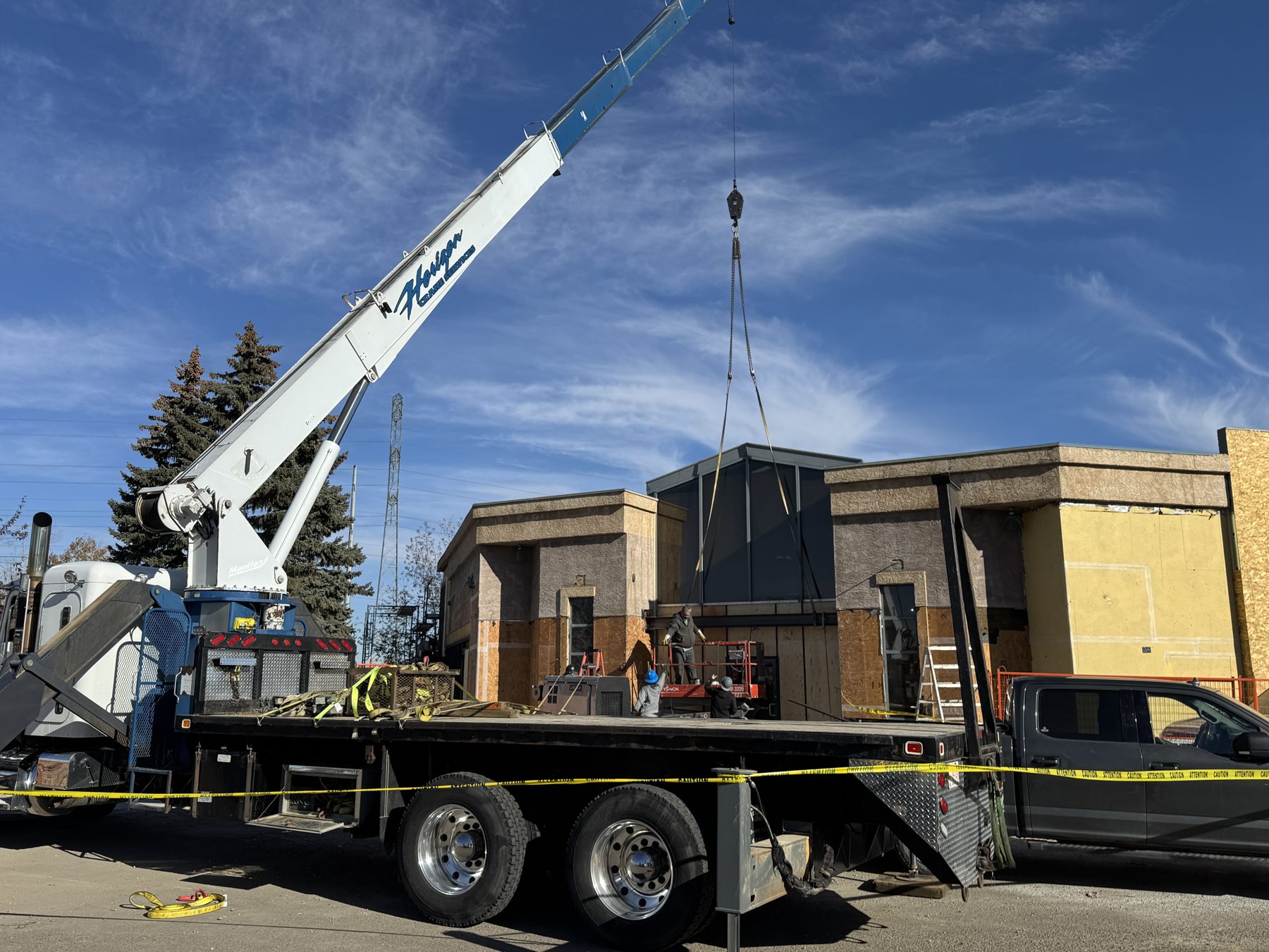 Crane lifting construction module onto unfinished building exterior — Blowers and Grafton (Red Deer)