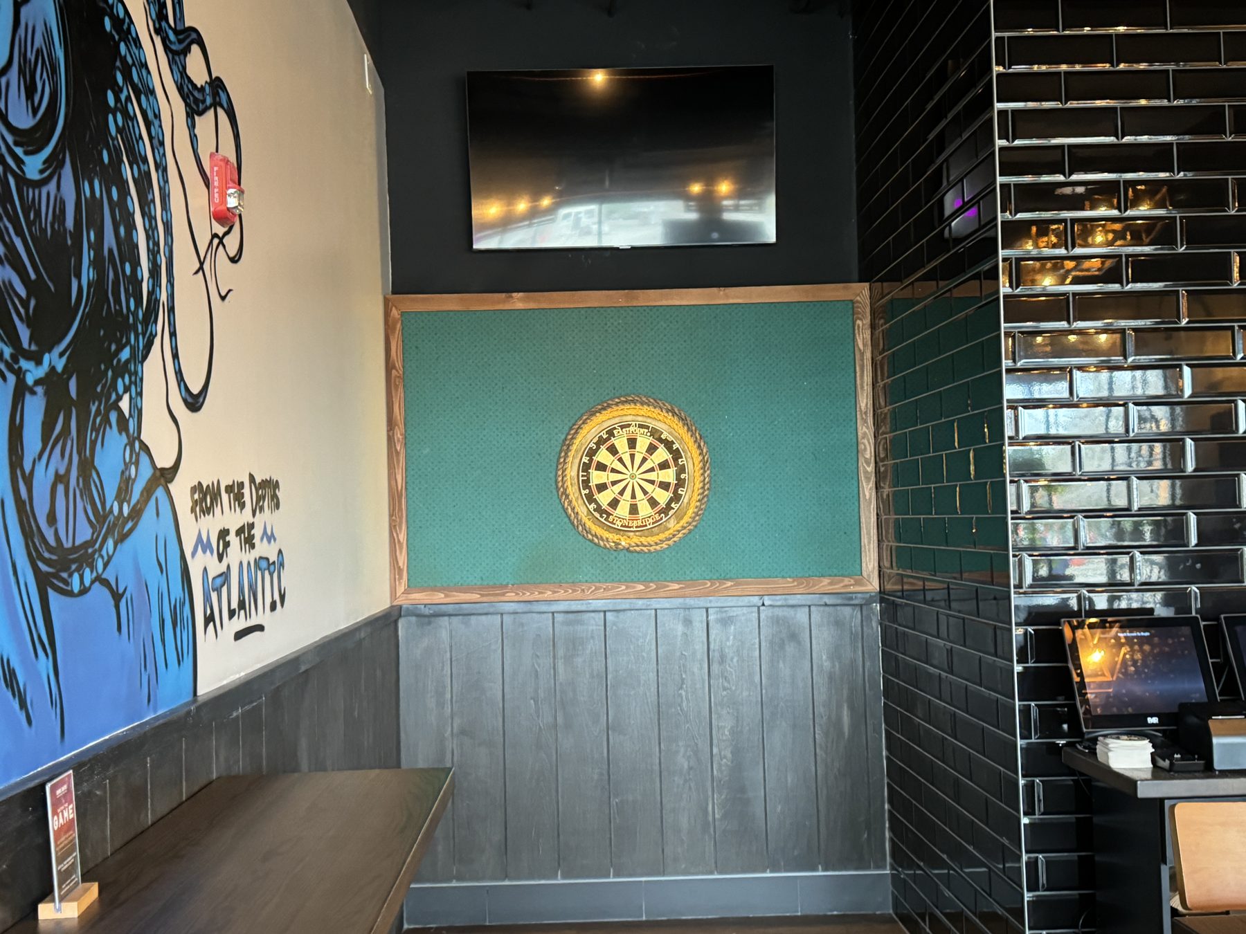 Dartboard on green wall paneling with black subway tile — Blowers and Grafton (Shawnessy)