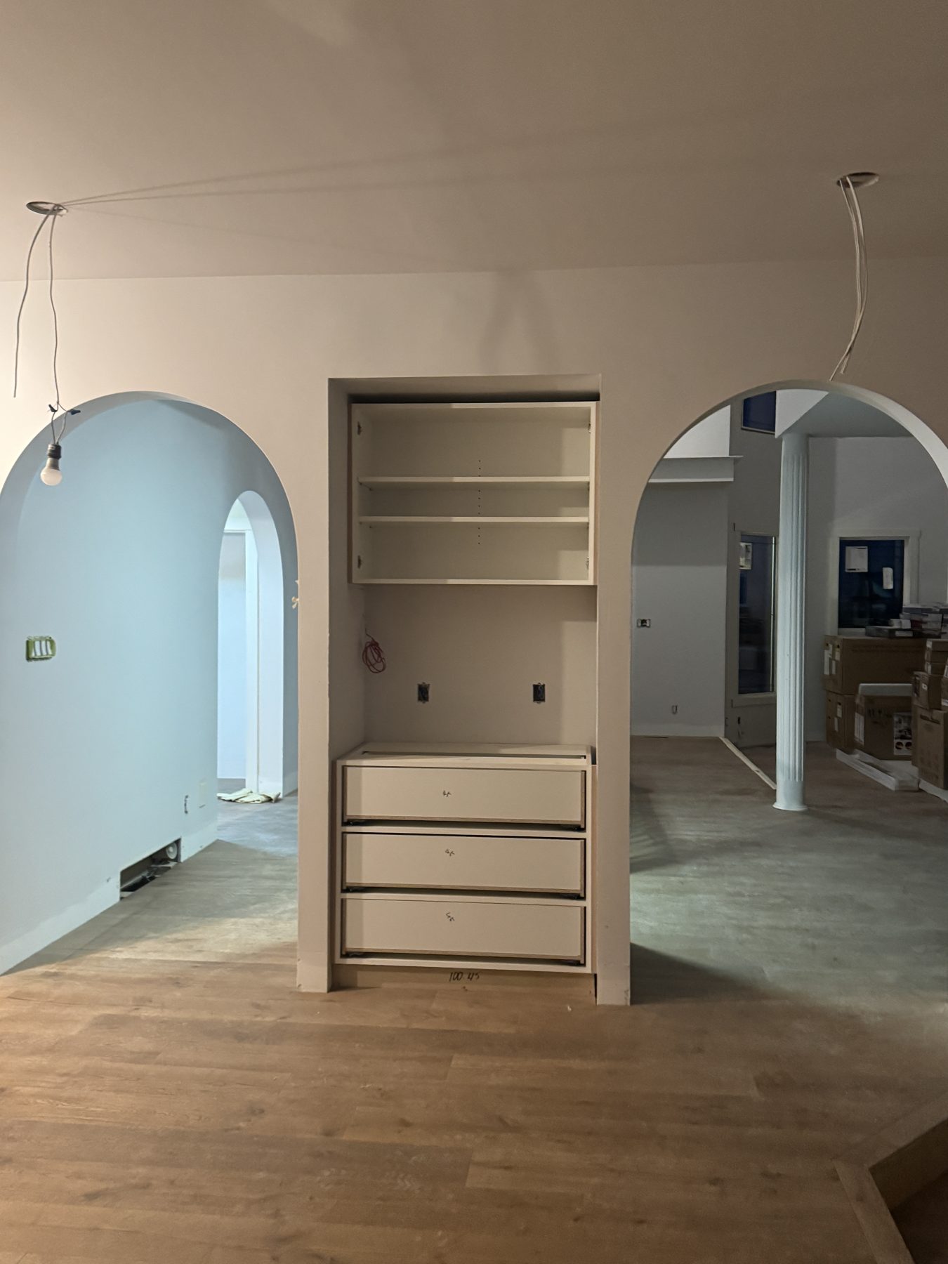 Hallway with arched doorways, unfinished built-in cabinets, and wood flooring — 14 Lochend Drive, Cochrane