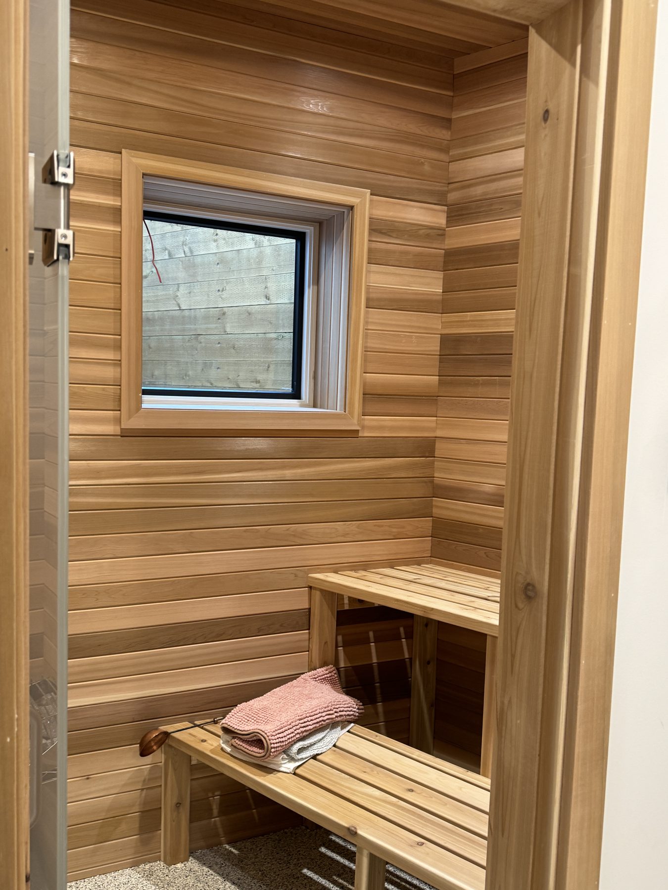 Cedar paneled sauna interior with wooden benches and a small window — 18 Varsplain Place Northwest