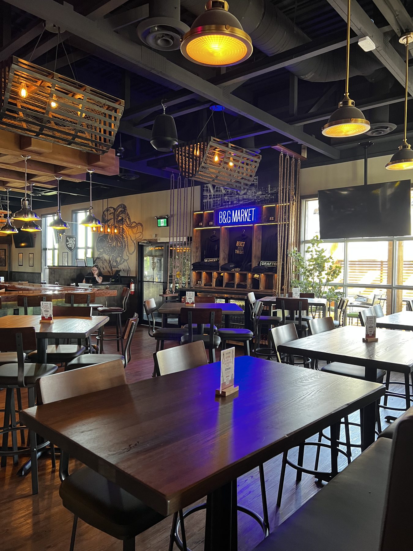 Restaurant dining area with wood tables, industrial lighting, and neon signage — Blowers and Grafton (Shawnessy)