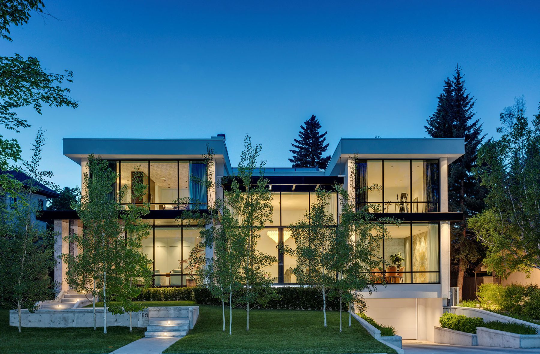 Modern house exterior at dusk, large windows, and lush landscaping — Modern Family by Onsite Contracting Services