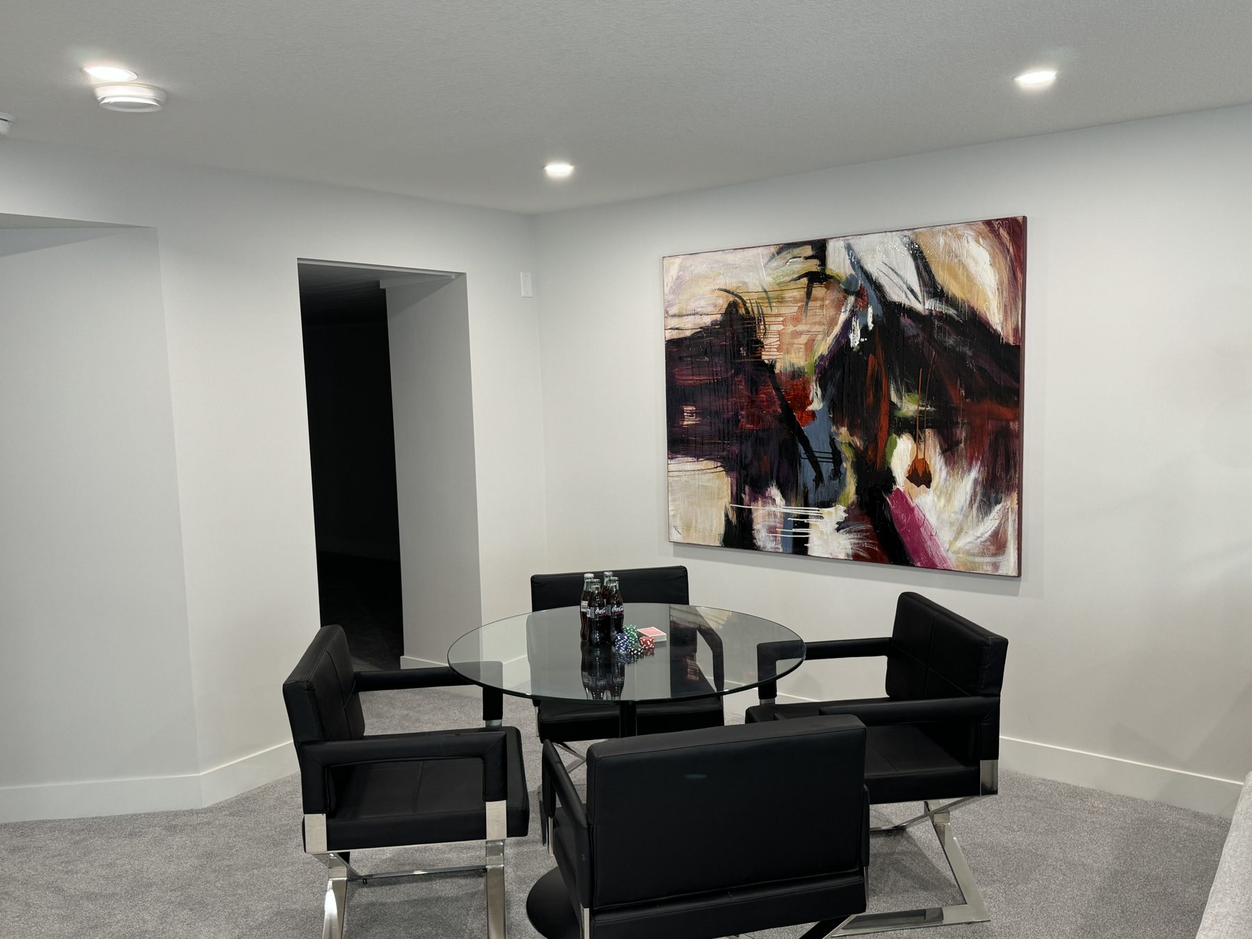 Modern game room with glass table, black chairs, and abstract art — Lake Bonavista