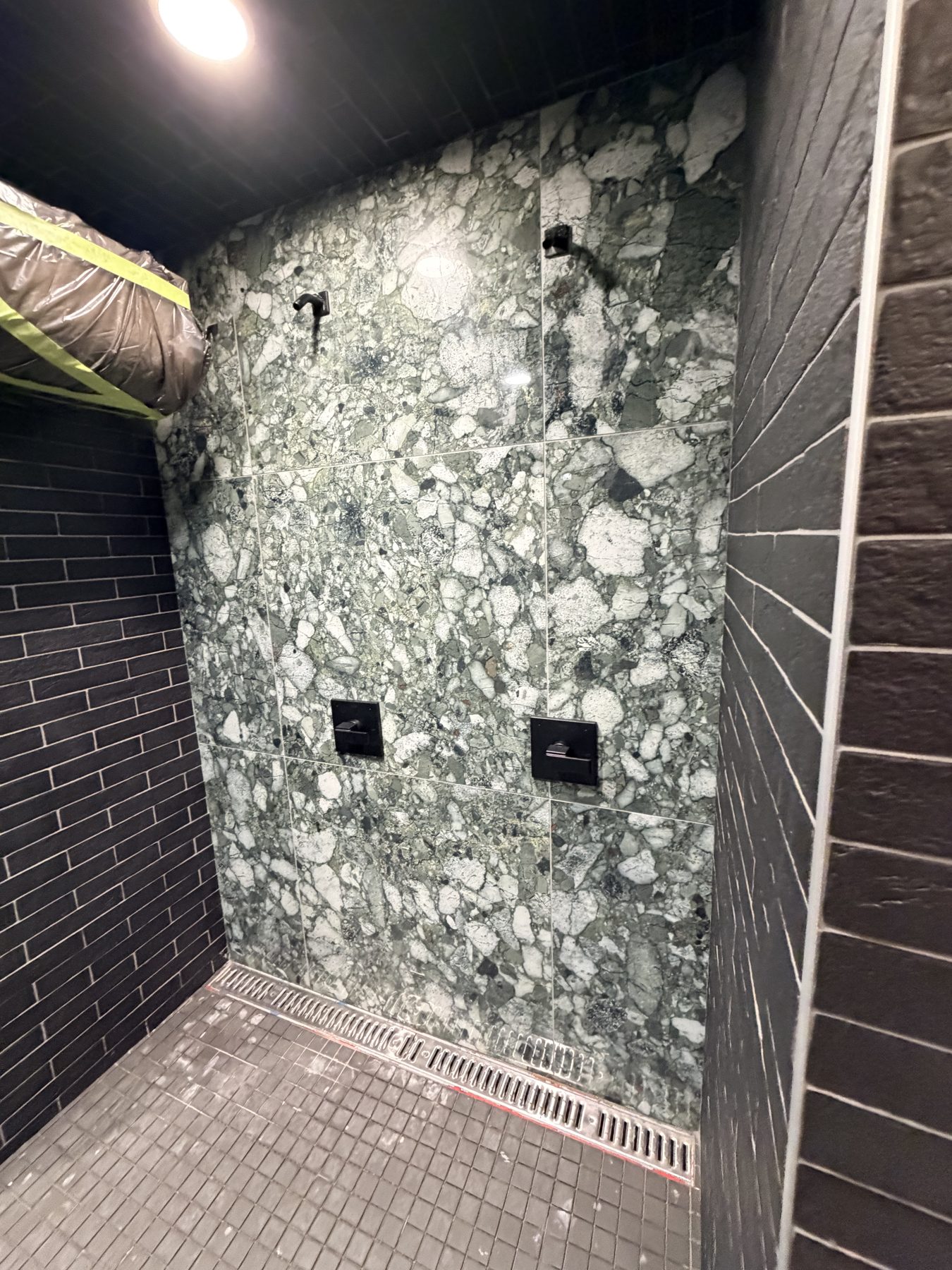 Shower under construction with marble tile, black tile, and drain — Cedar Steam and Spa (Trinity Hills)