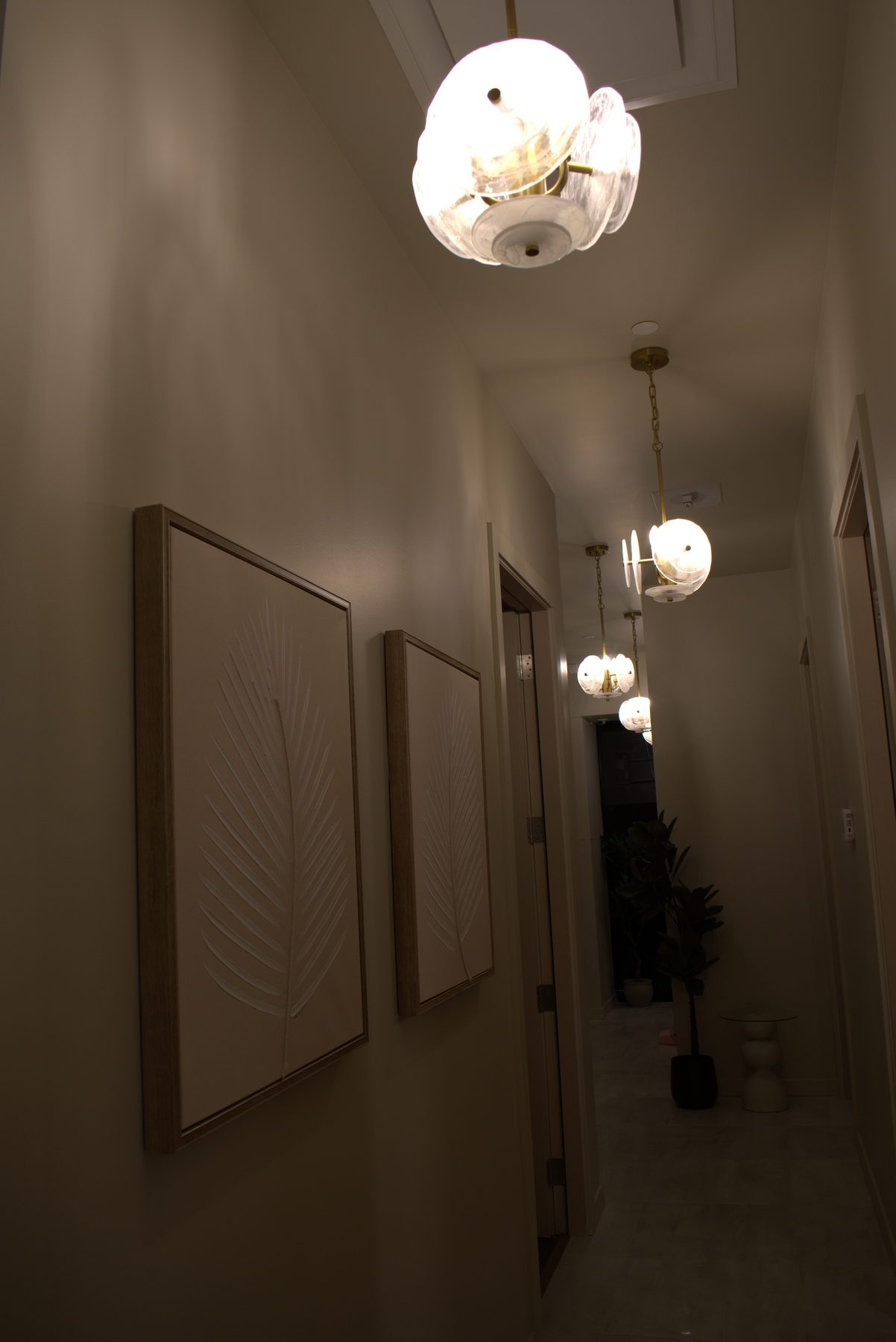 Hallway with modern pendant lights and framed botanical art — Leela Spa (Bankers Hall)