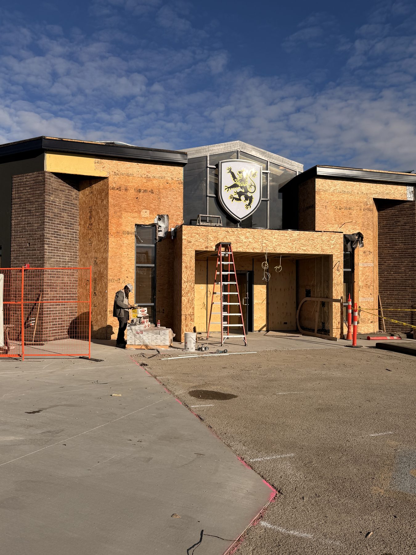 Exterior construction on building with plywood, brick, and emblem — Blowers and Grafton (Red Deer)