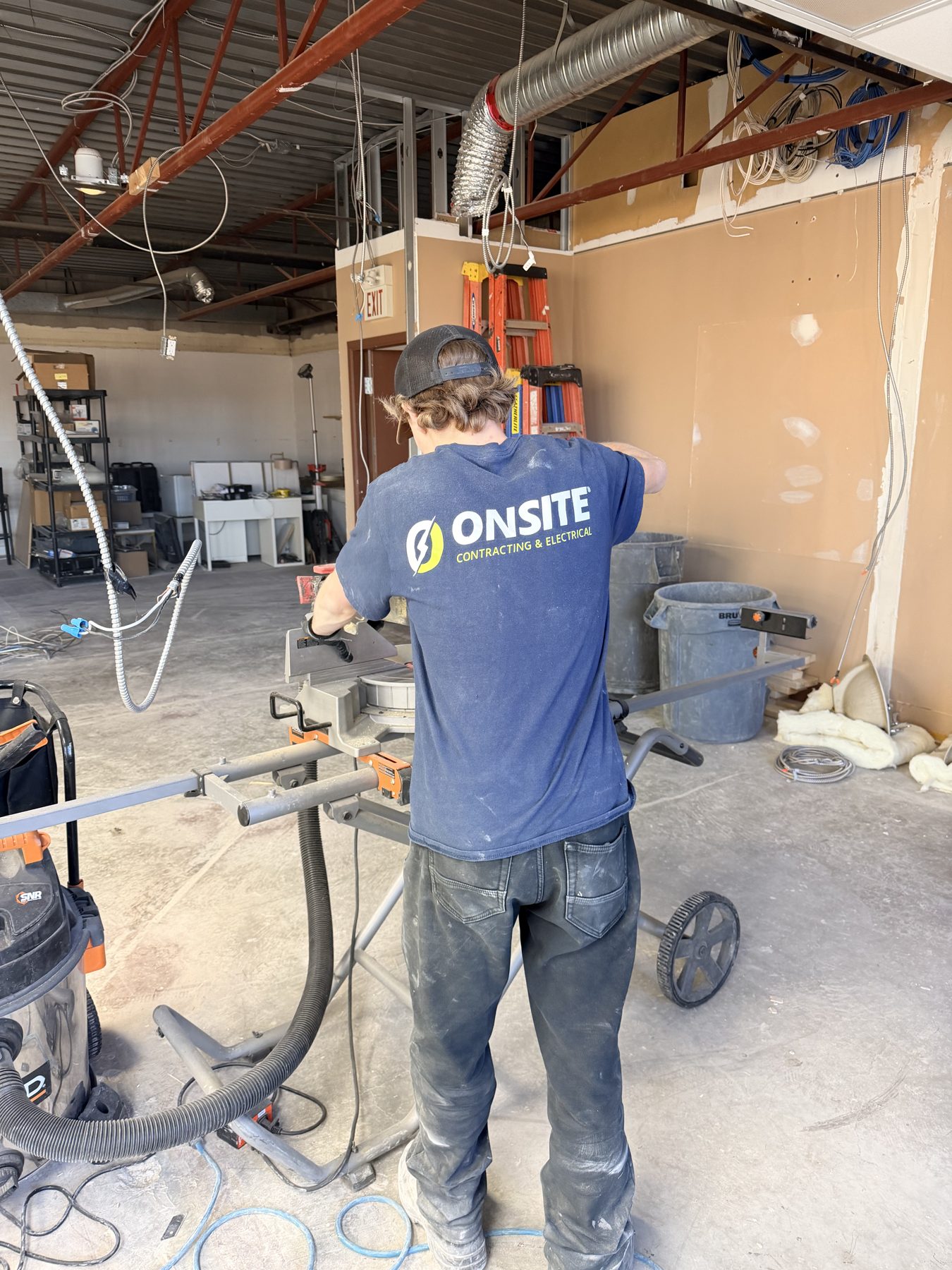 Construction worker cuts metal with miter saw in unfinished room — The Barron Venue