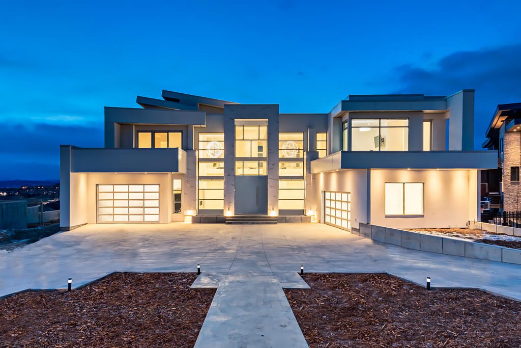 Modern home exterior with glass garage doors and large windows — Blanc de Blanc by Onsite Contracting Services