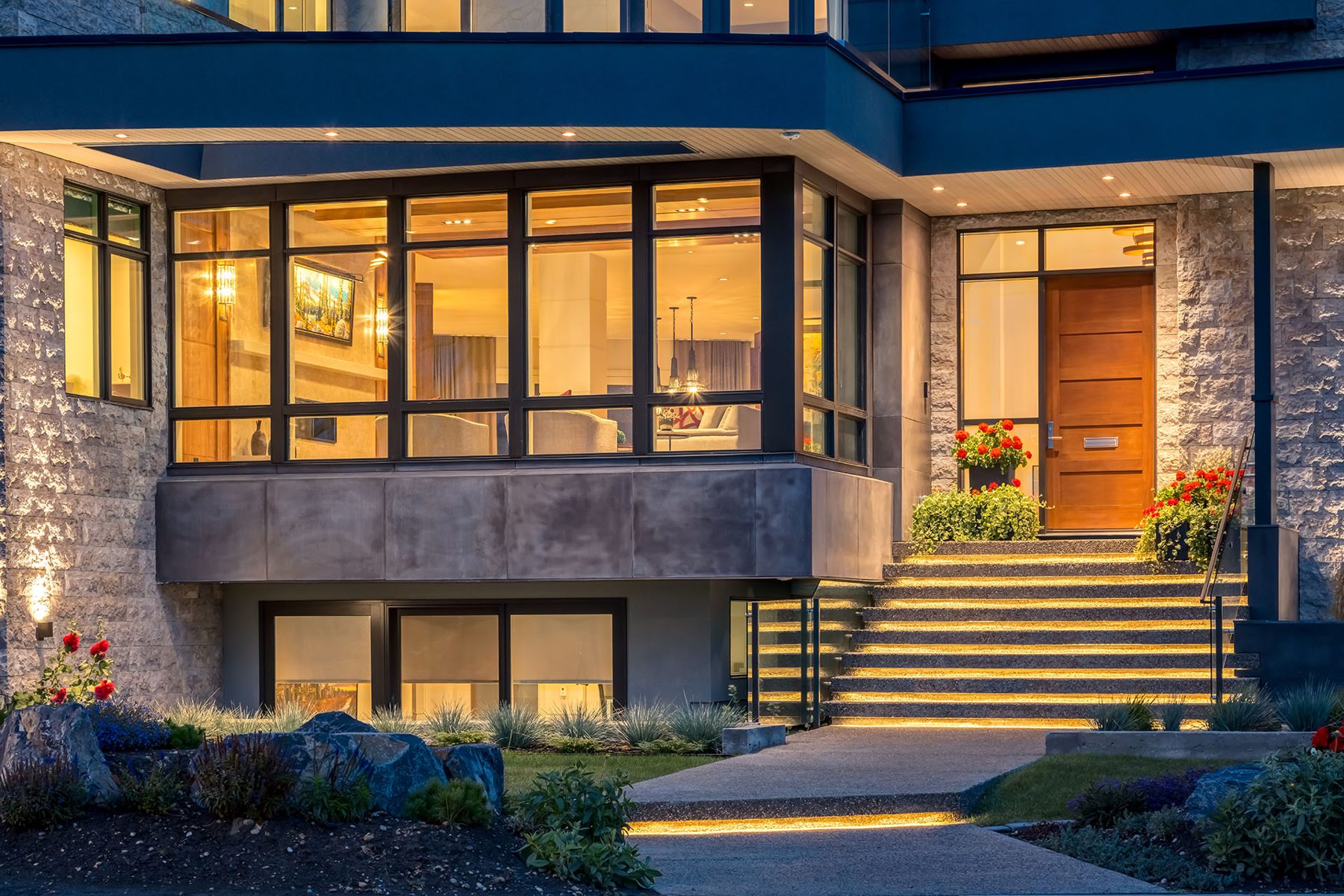 Modern house entrance with stone facade, wood door, and illuminated stairs — Evolution