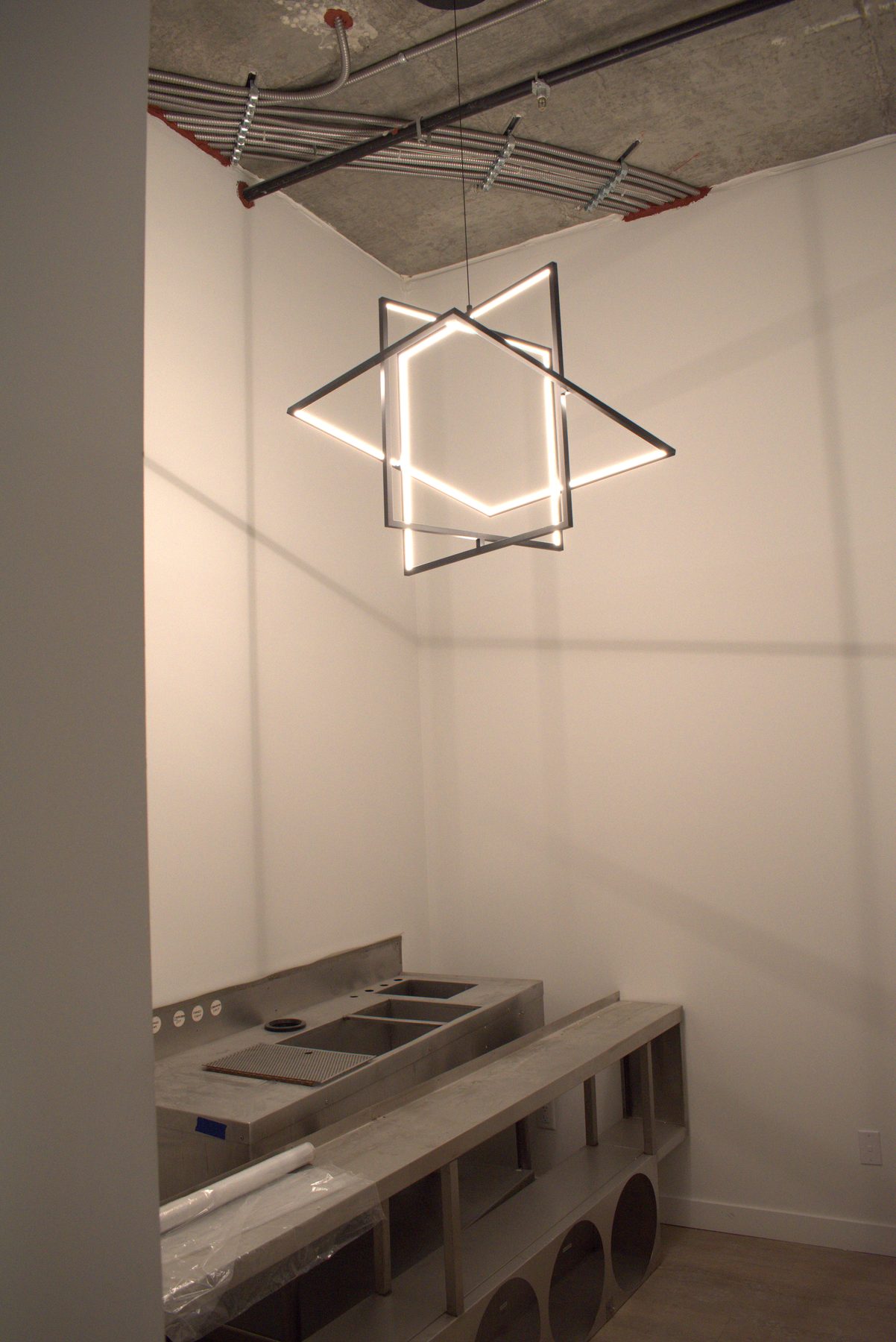 Metal counter with sinks and modern geometric light fixture installed — Big Buns (Bowness)