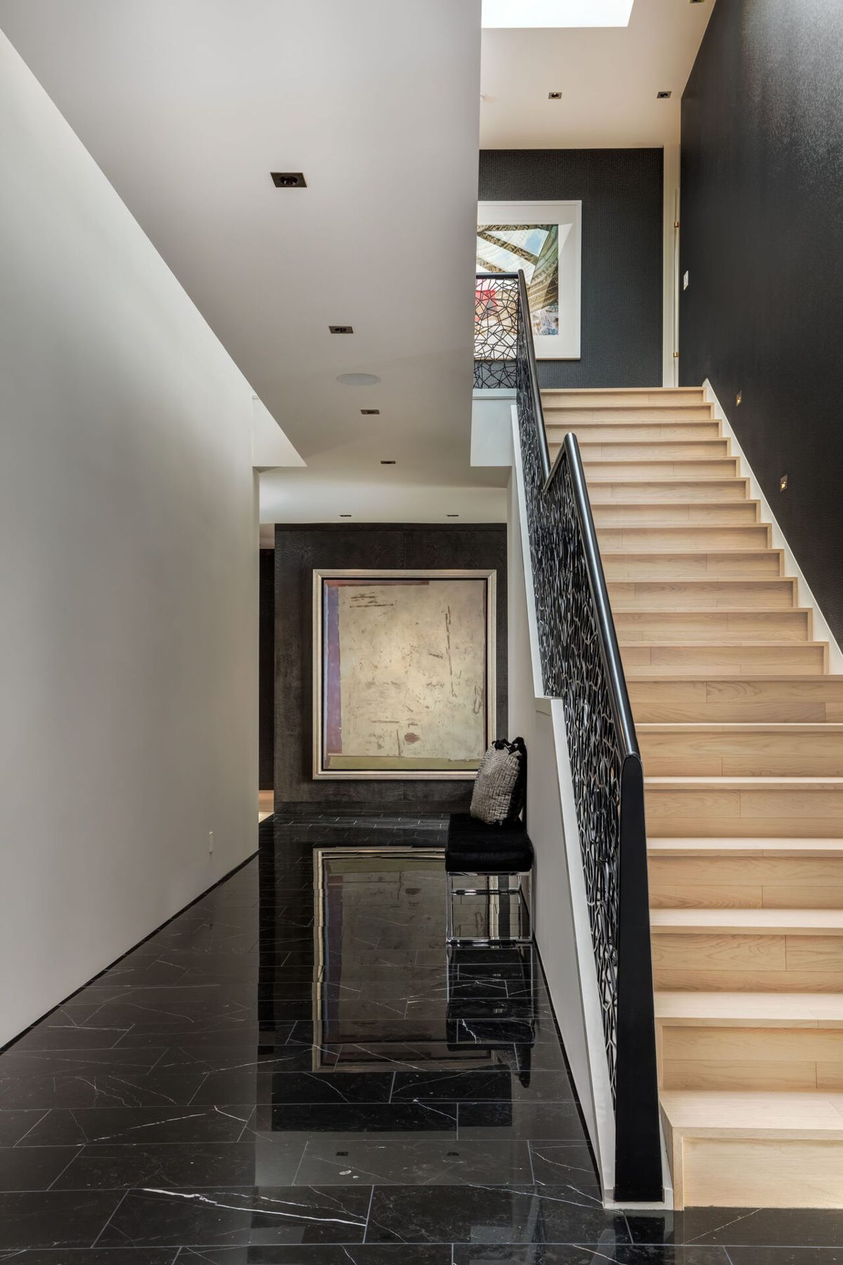 Modern hallway with black marble floor and light wood stairs — Modern Family