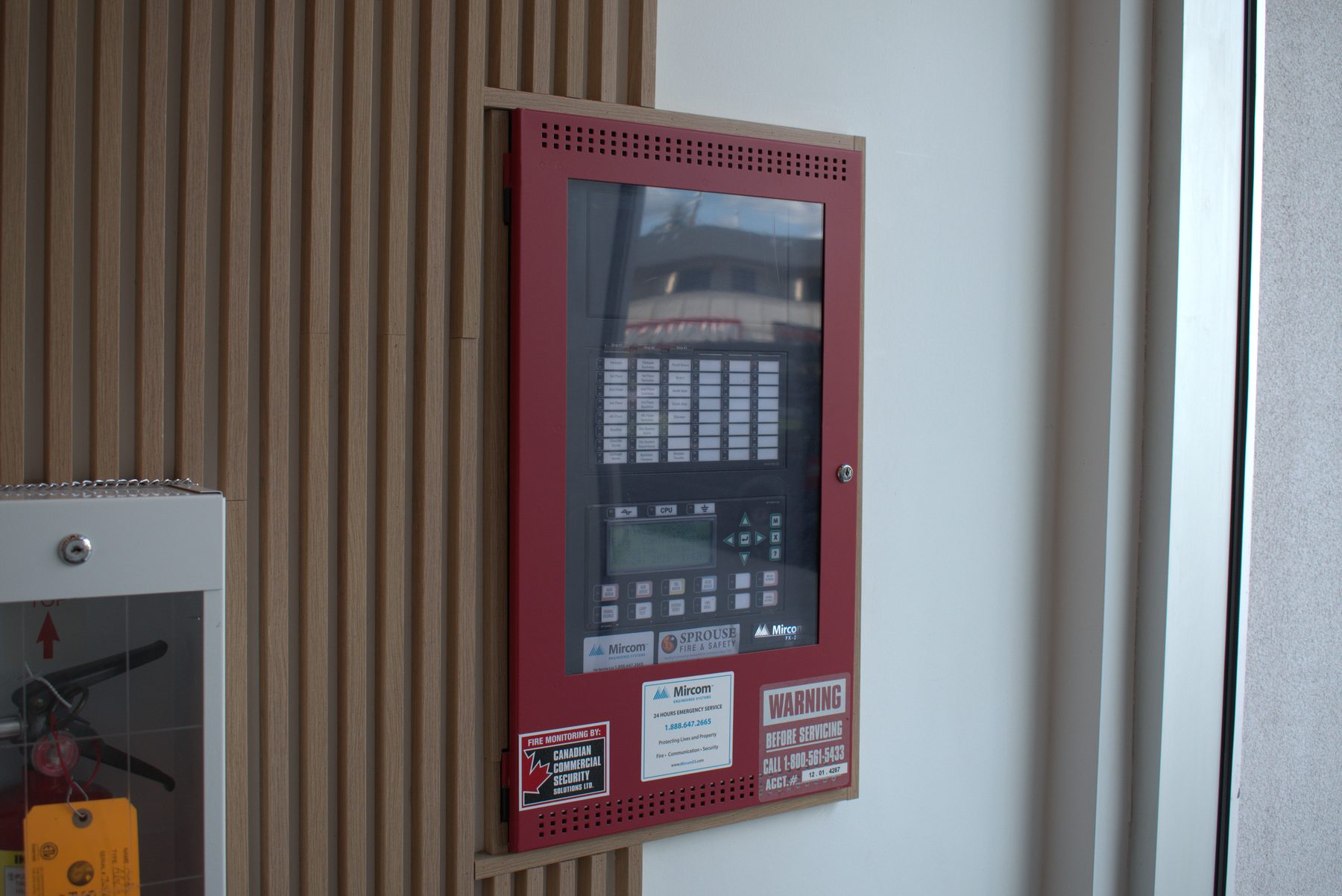 Red fire alarm panel installed on a slatted wood wall — Big Buns (Bowness)