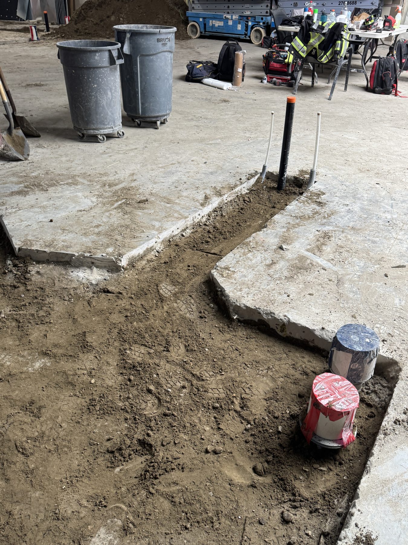 Concrete floor opened with new plumbing pipes and caps visible — Blowers and Grafton (Red Deer)