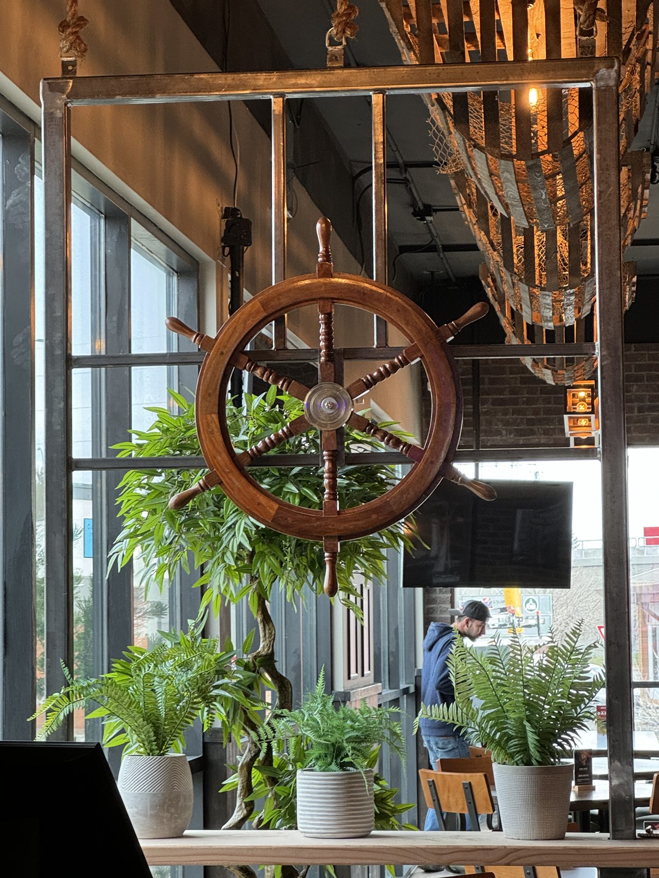 Nautical decor features wooden ship's wheel, plants, and metal frame — Blowers and Grafton (Shawnessy)